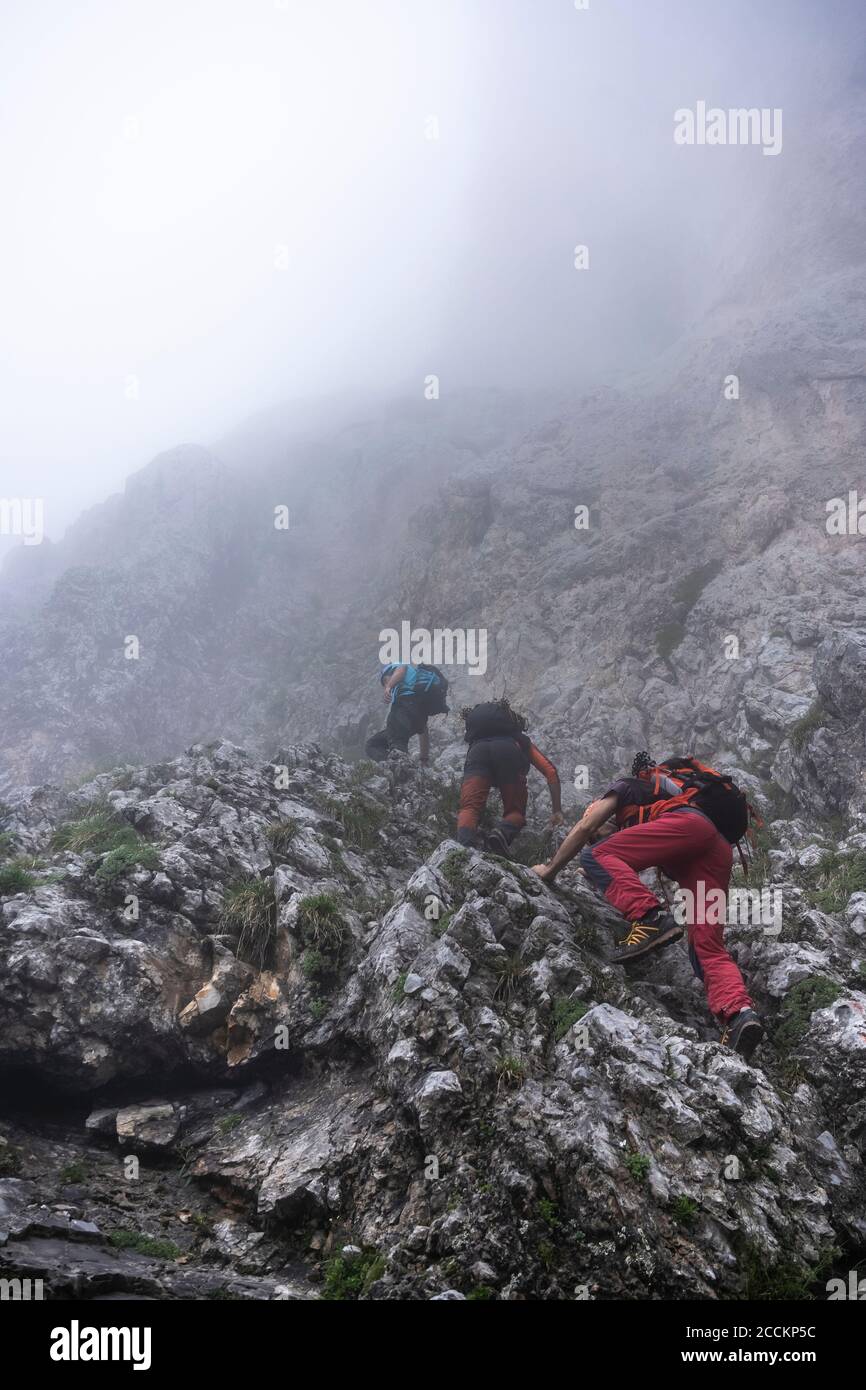 Hommes matures grimpant sur la montagne par temps brumeux, Alpes de Bergame, Italie Banque D'Images