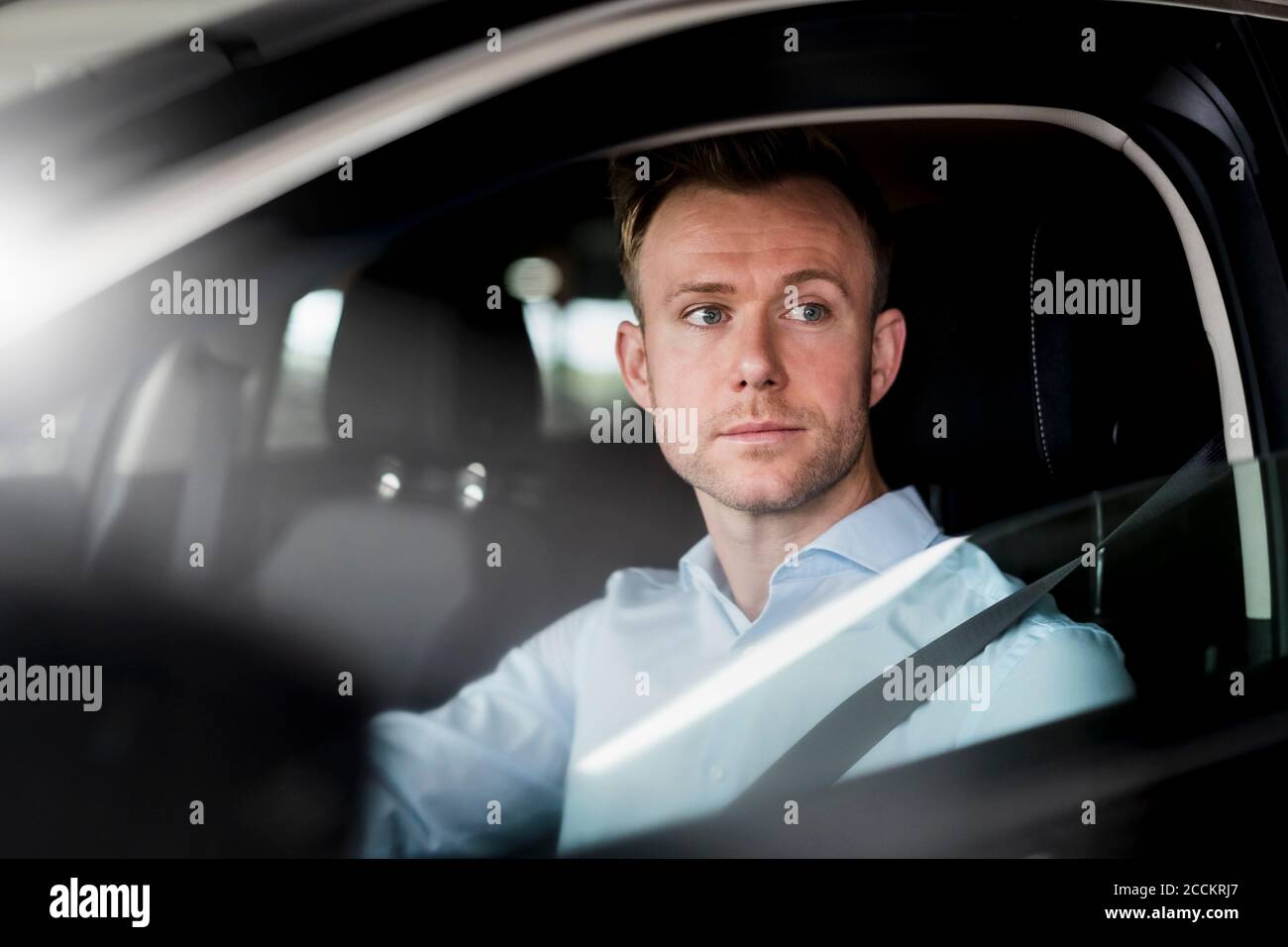 Un entrepreneur sérieux qui regarde loin en étant assis en voiture Banque D'Images