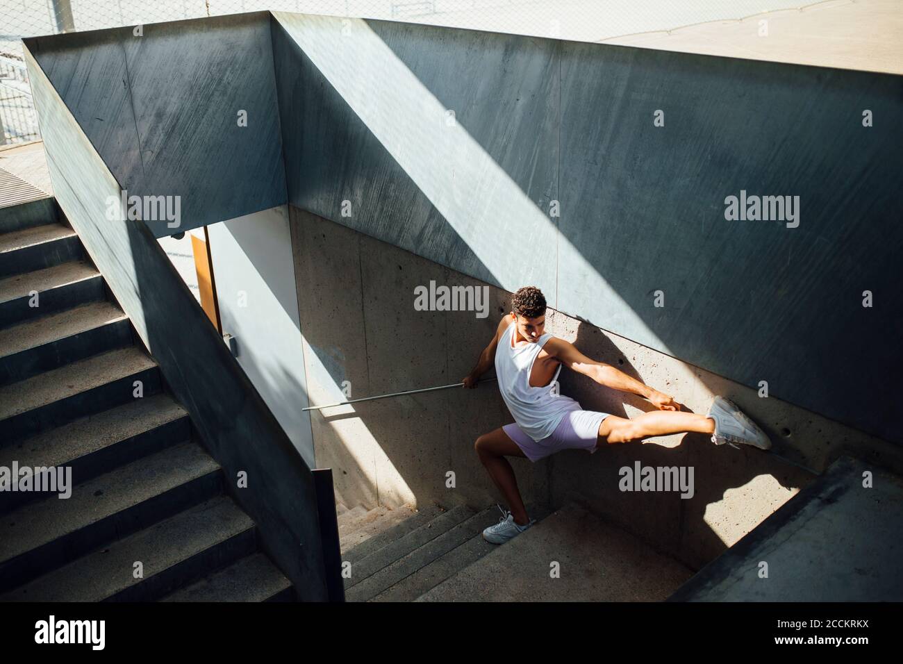 Jeune homme faisant un exercice gymnastique rythmique sur les marches par mur Banque D'Images