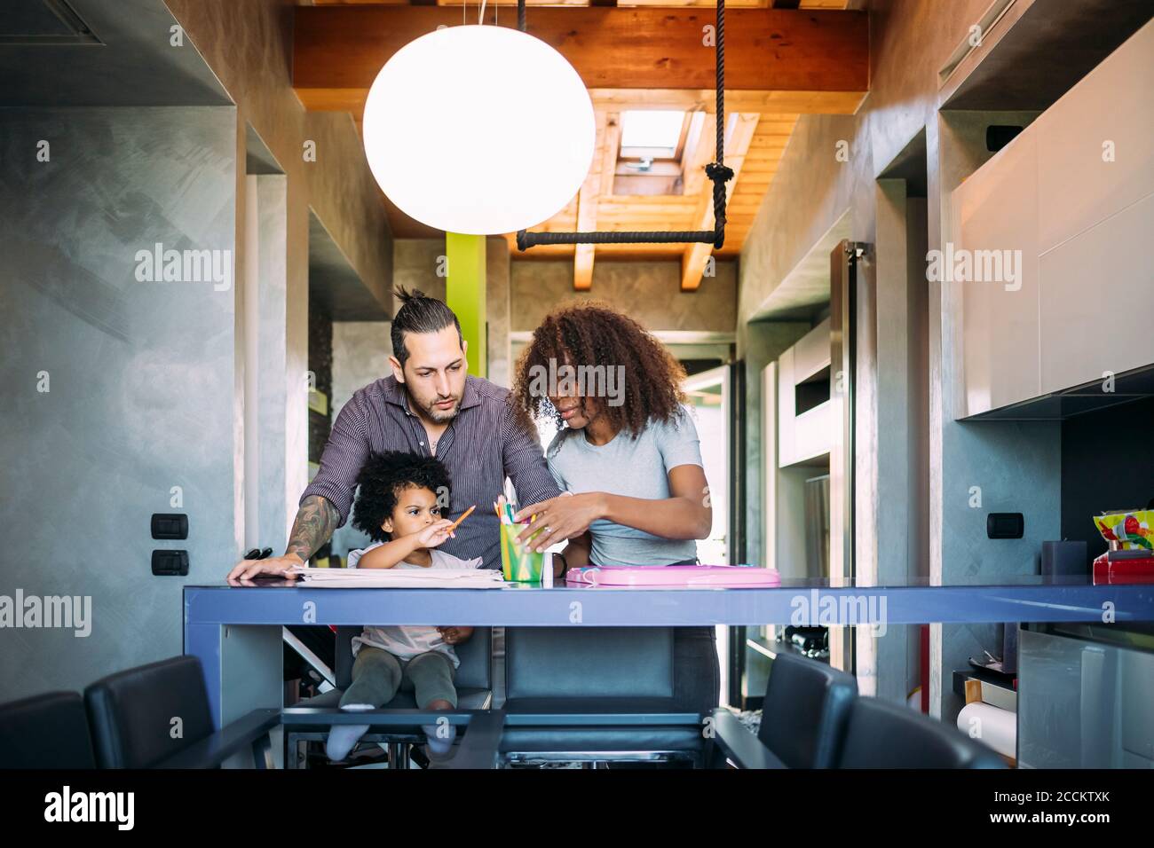 Parents et fille choisissant un crayon de couleur sur la table à la maison Banque D'Images