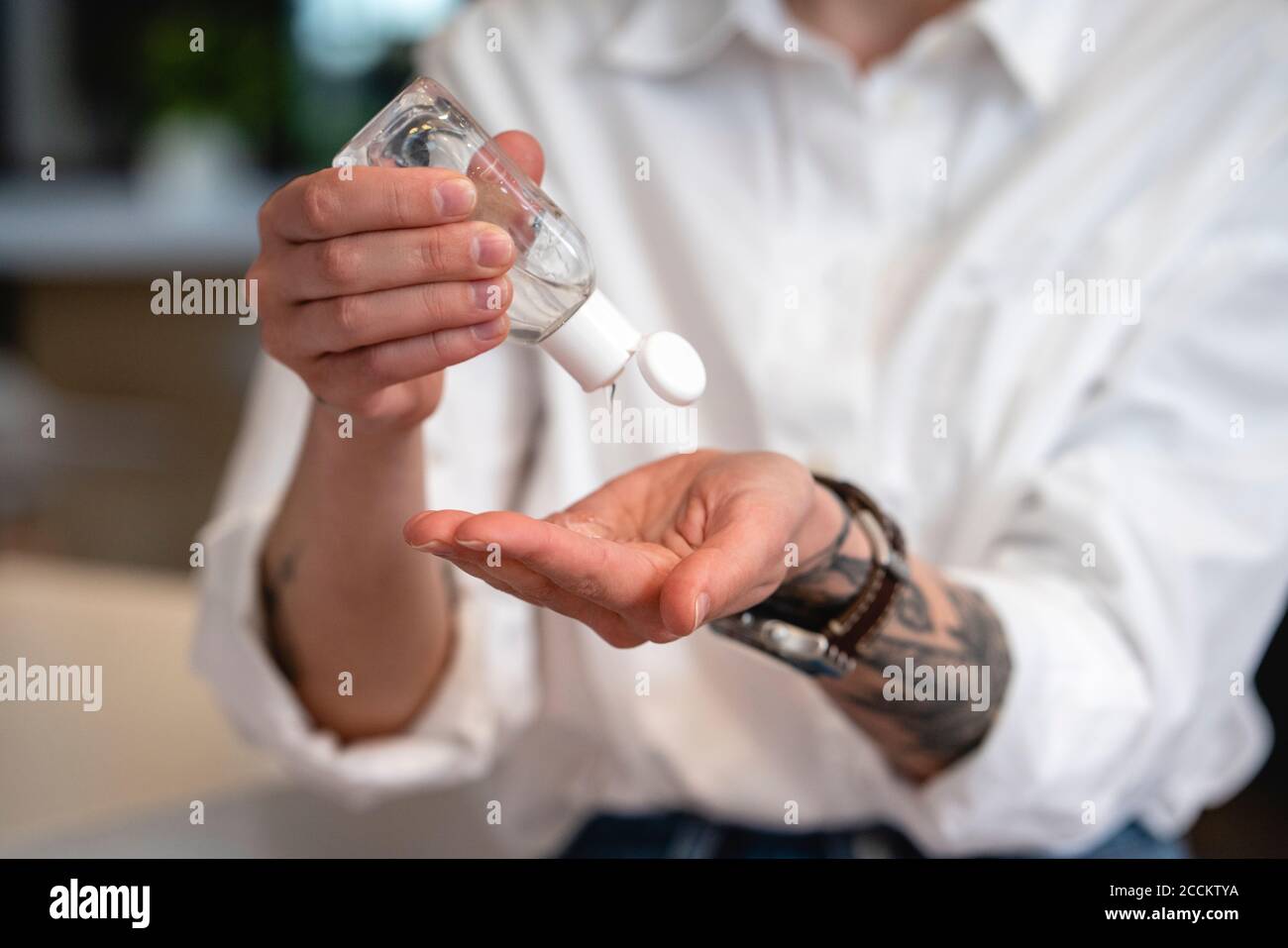 Femme entrepreneur désinfectant les mains avec de l'assainisseur à la cafétéria du bureau pendant pandémie Banque D'Images