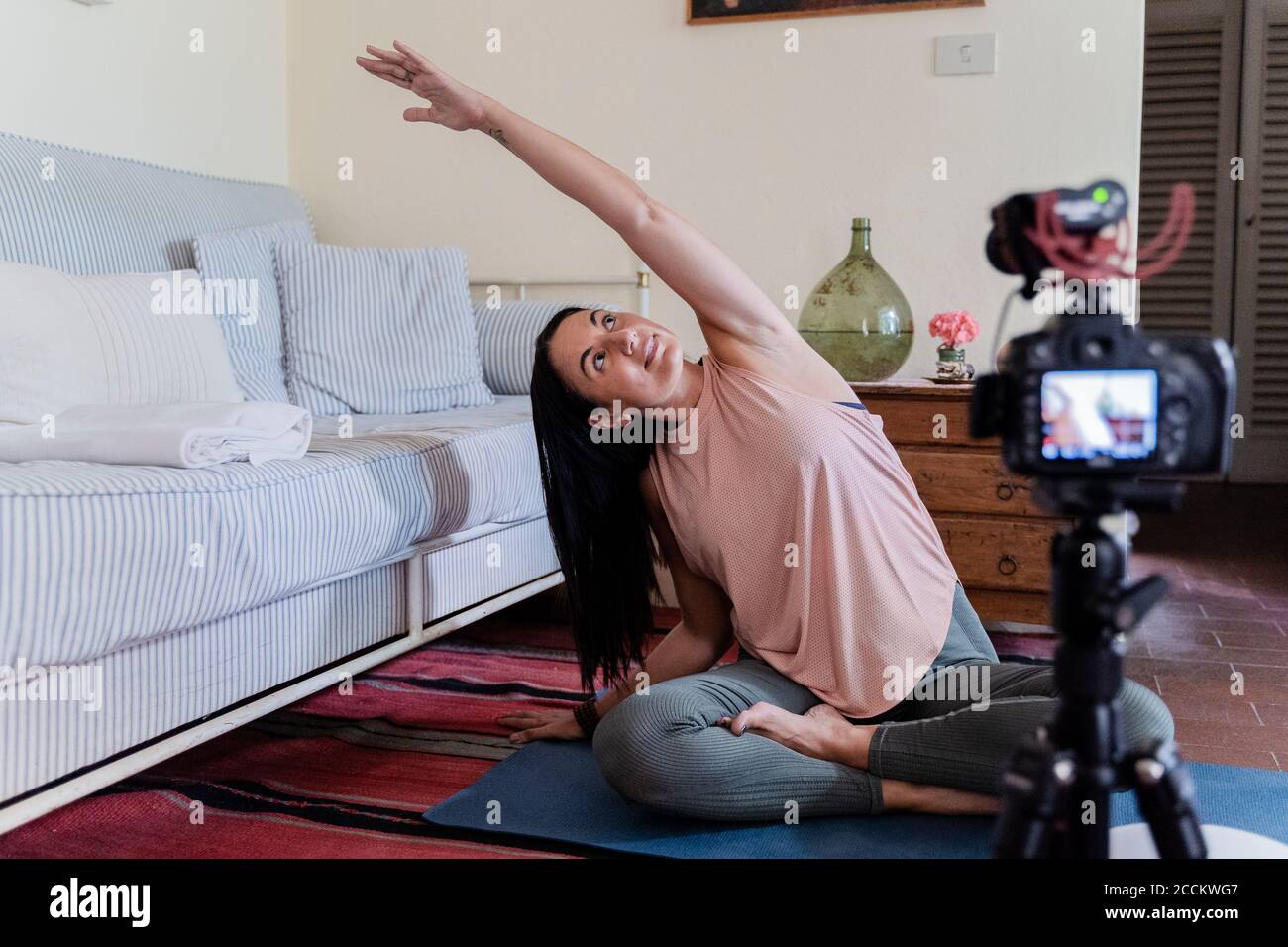 Femme mûre souriante pendant l'exercice de yoga devant le numérique appareil photo Banque D'Images