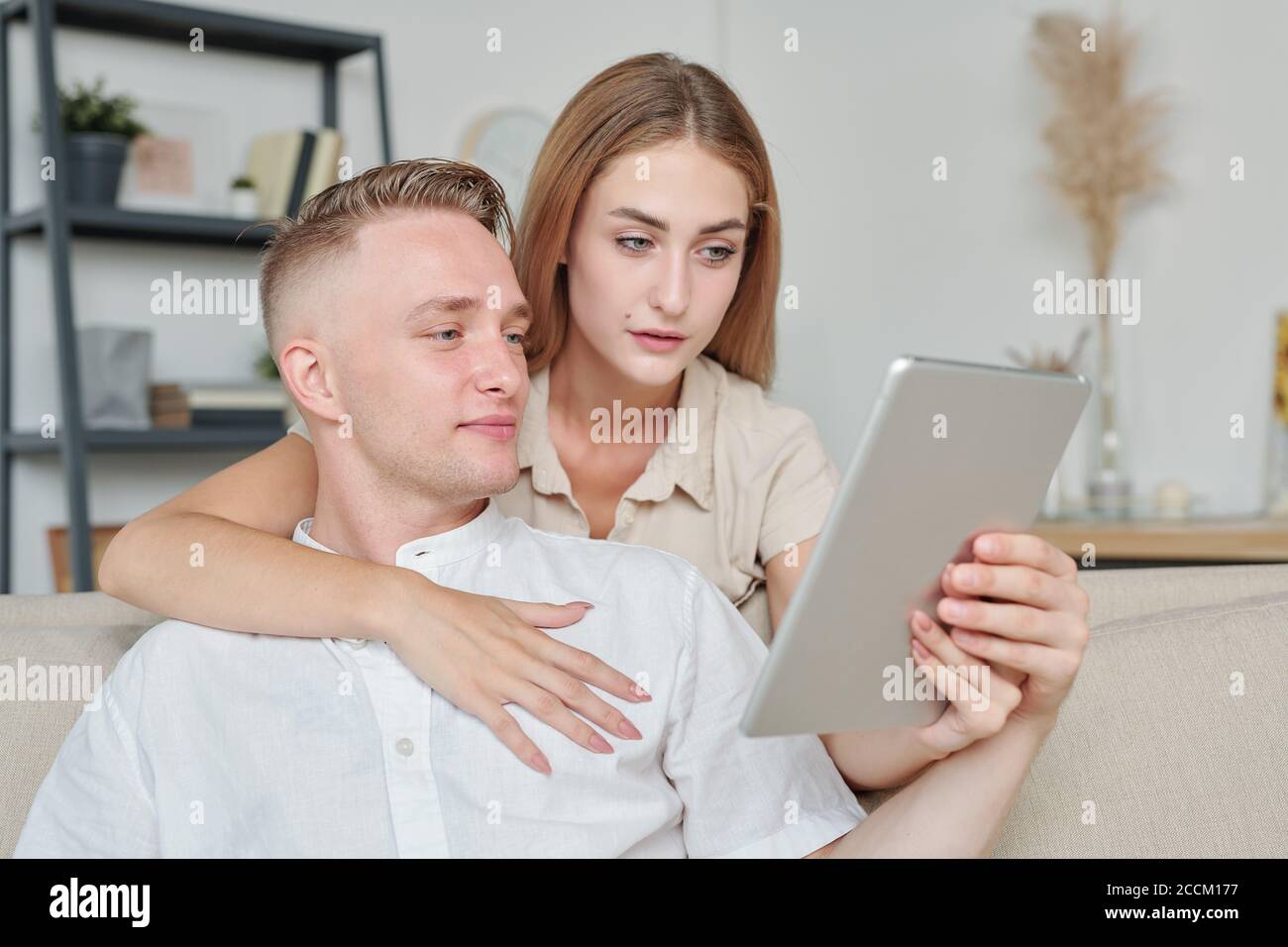 Femme affectueuse avec une tablette montrant le mari Nice habits en ligne boutique Banque D'Images