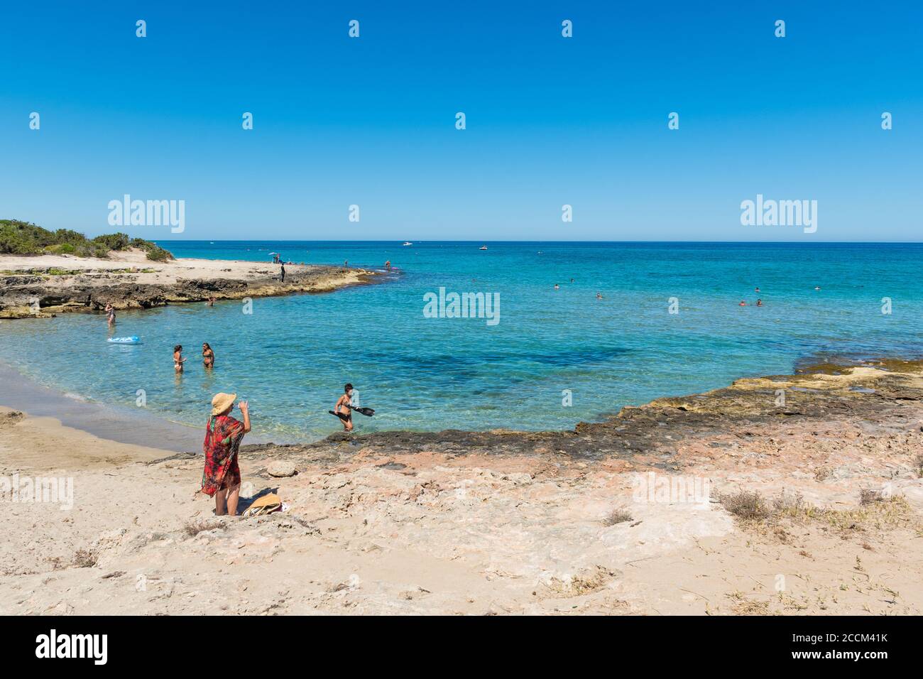 Magnifique plage de la côte méditerranéenne à Puglia, en Italie du Sud, avec des baigneurs dans l'eau cristalline Banque D'Images
