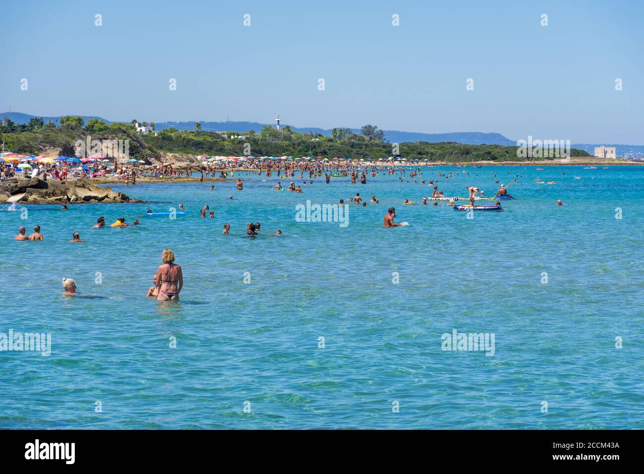 Magnifique plage de la côte méditerranéenne à Puglia, en Italie du Sud, avec des baigneurs dans l'eau cristalline Banque D'Images