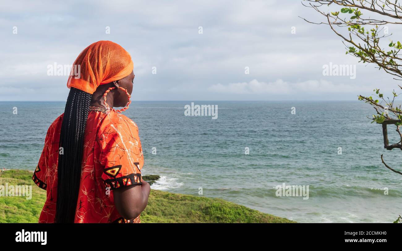 Priant une femme africaine portant une robe traditionnelle orange du Ghana regarde À l'horizon à Takoradi Ghana Afrique de l'Ouest Banque D'Images
