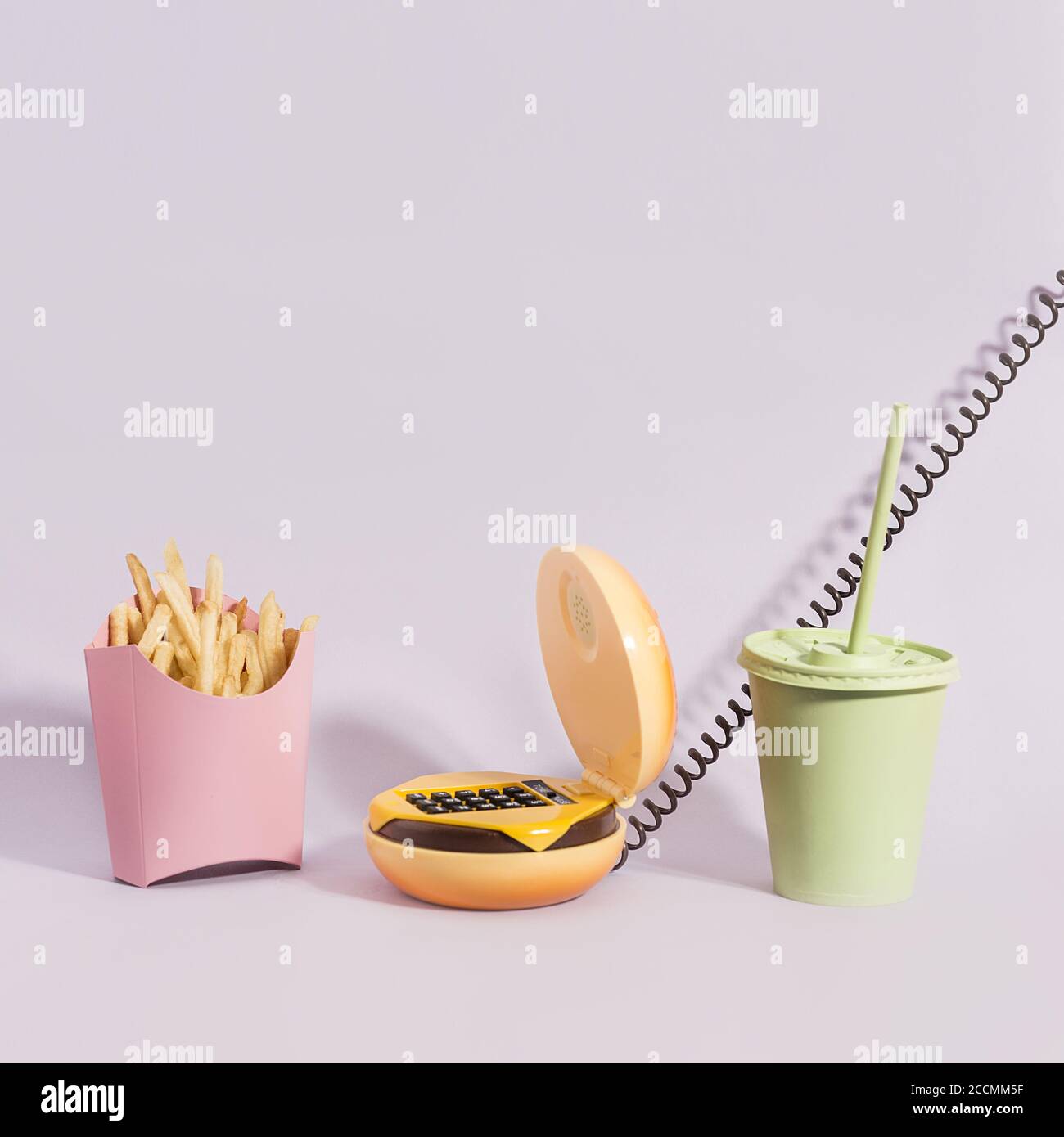 Photo minimaliste de frites dans un emballage en papier, gobelet en papier et téléphone à hamburger au milieu Banque D'Images