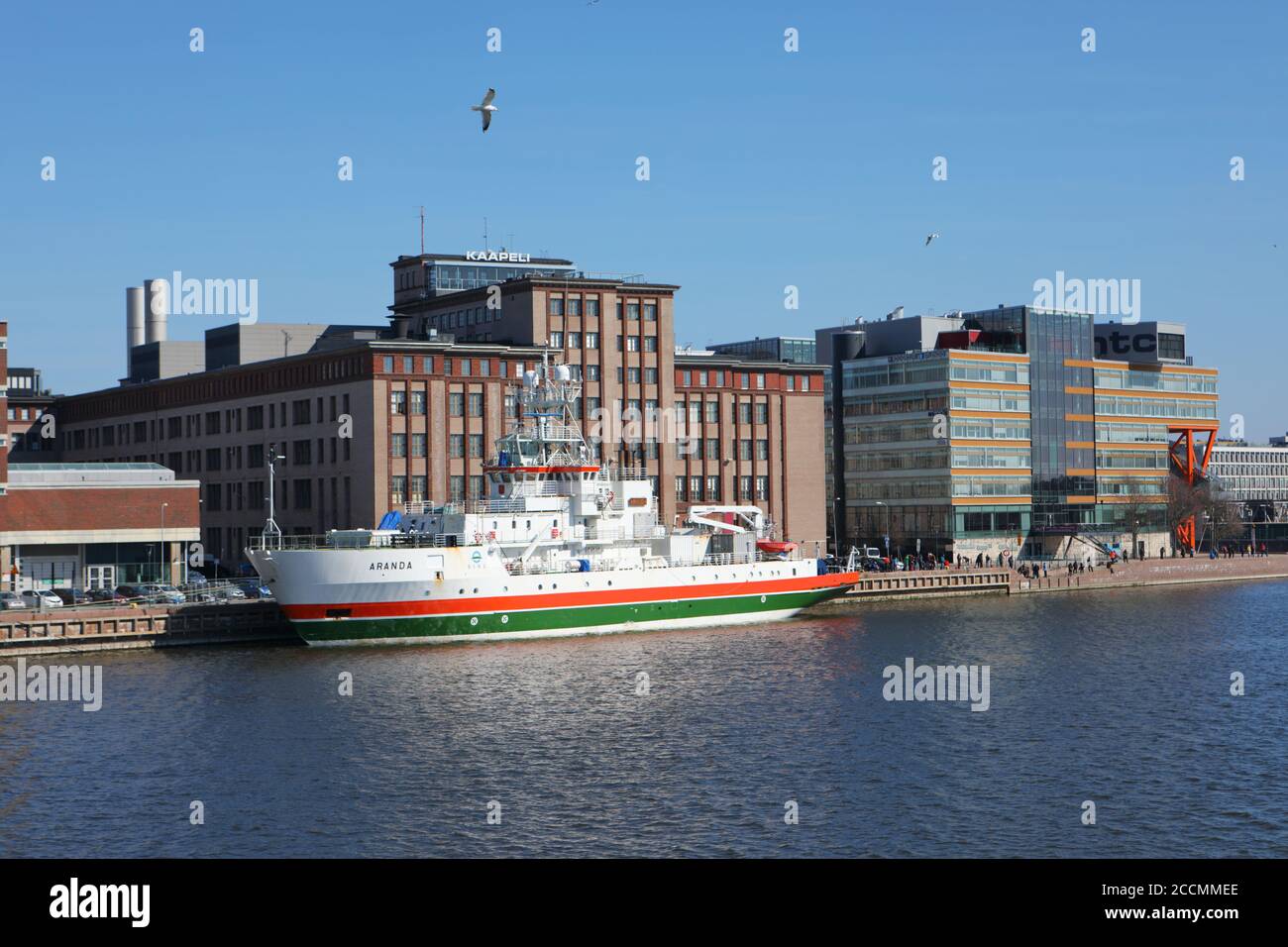 Bateau nautique à rayures orange et vertes amarré à Salmisaari, Helsinki, Finlande, devant l'ancienne fabrique de câbles, aujourd'hui espace culturel Banque D'Images