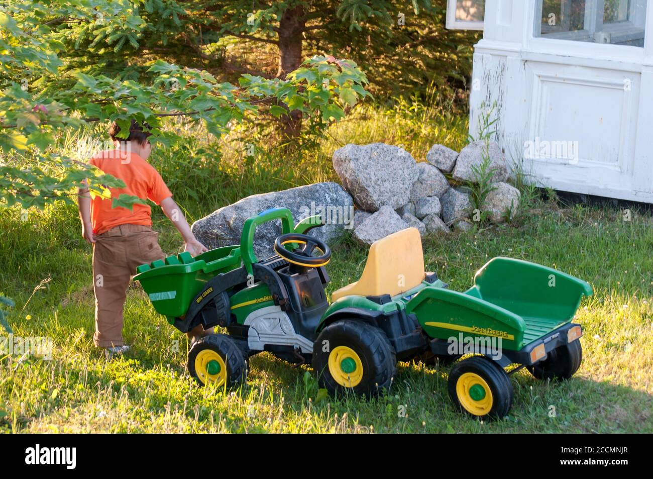 Un jeune garçon tire son jouet géant de tracteur dans une cour, en Nouvelle-Écosse, au Canada Banque D'Images