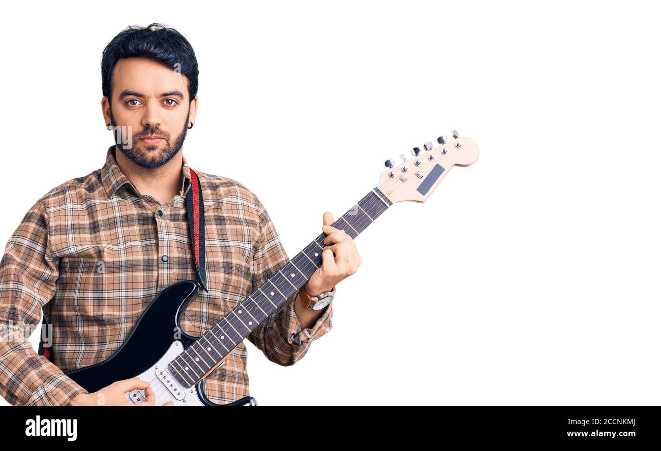 Jeune homme hispanique jouant de la guitare électrique pensée attitude et sobre expression en toute confiance Banque D'Images