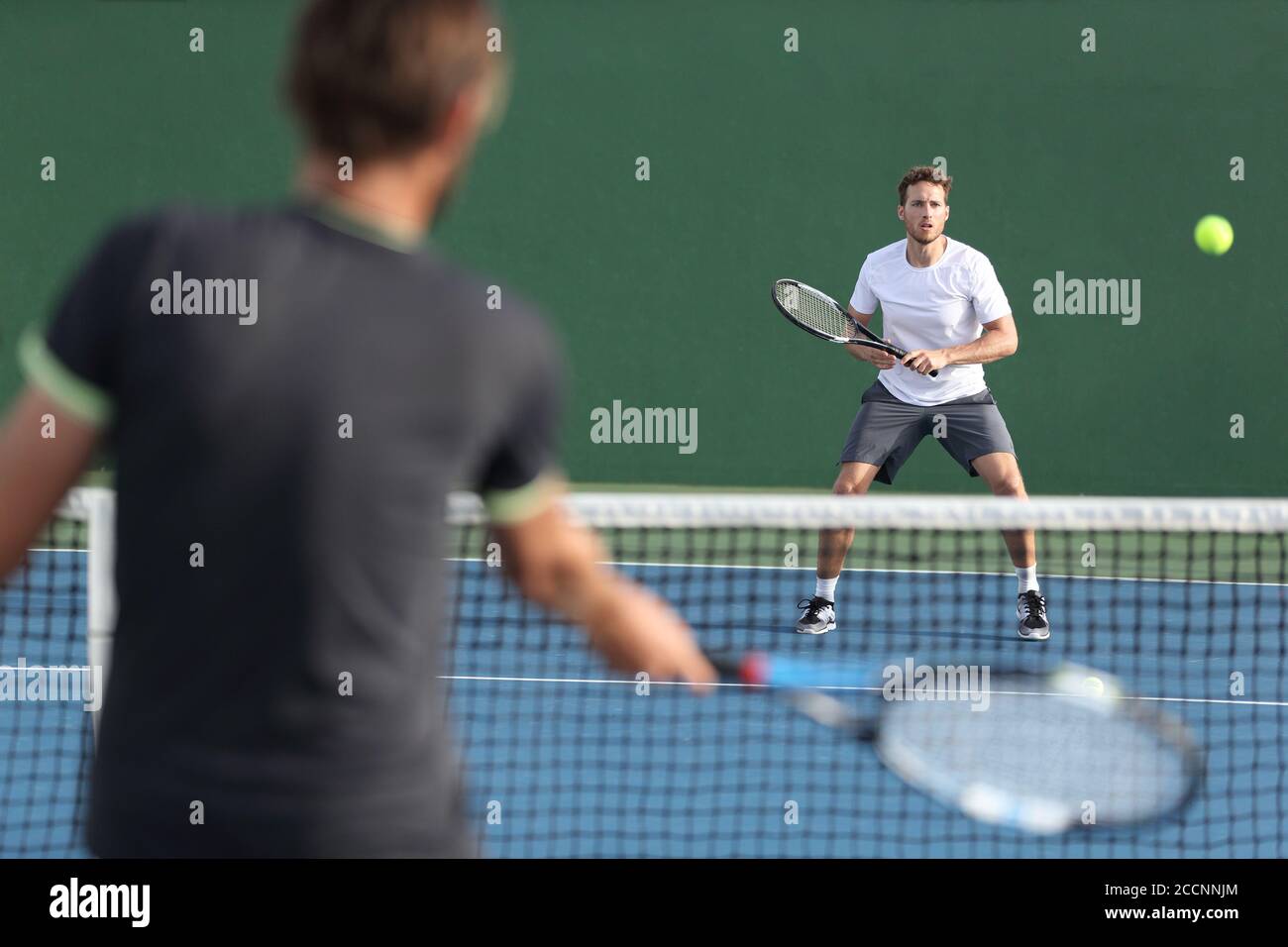 Hommes athlètes sportifs joueurs jouant au tennis ensemble. Deux joueurs de tennis professionnels qui frappent le ballon sur un terrain dur en plein air pendant le match Banque D'Images