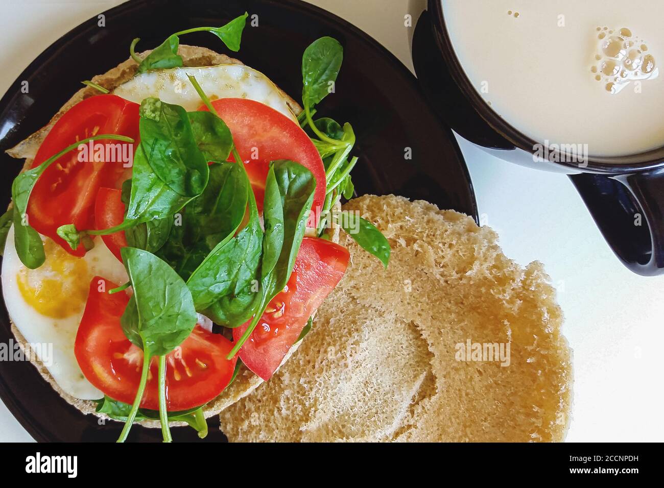 repas du petit déjeuner maison - oeufs frits avec tomate et épinards frais sur pita, thé avec lait Banque D'Images