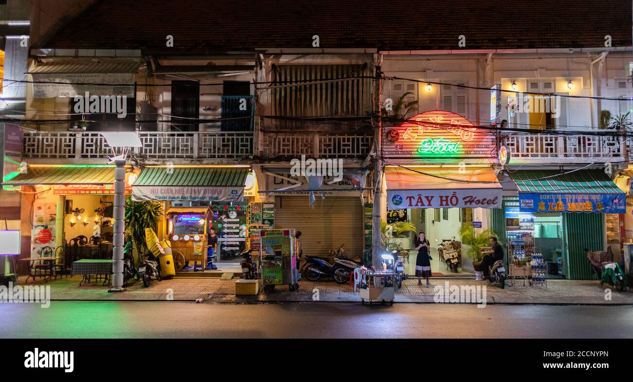 Rue commerciale la nuit. Magasins, maisons de style chinois, entreprises, terrasses de restaurants, gens. Auvents avec des mots vietnamiens. CAN Tho, Vietnam Banque D'Images