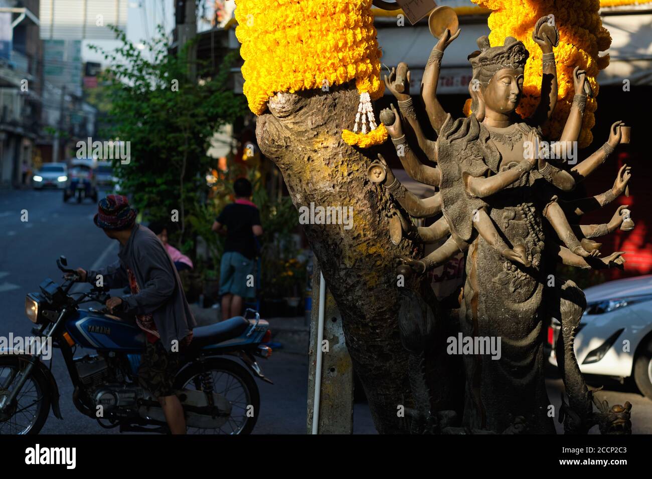 La statue d'une déesse de type hindou taoïste multi-armée, illuminée par la lumière du matin, debout à Bamrung Muang Rd., Bangkok, Thaïlande Banque D'Images