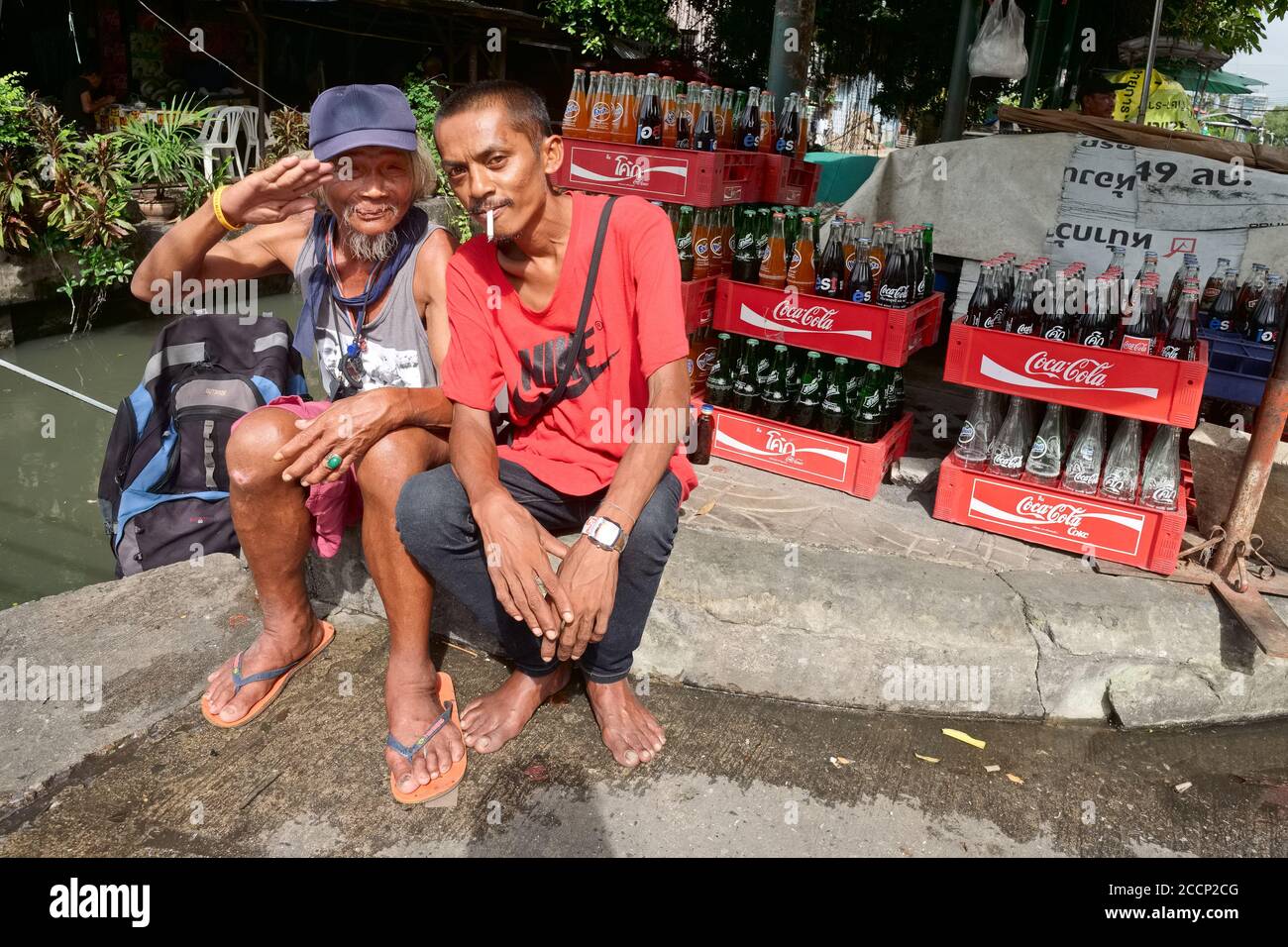 Deux hobos heureux, pas tout à fait sobres le prenant facilement par un klong (canal) à Bangkok, Asie du Sud-est, Thaïlande Banque D'Images