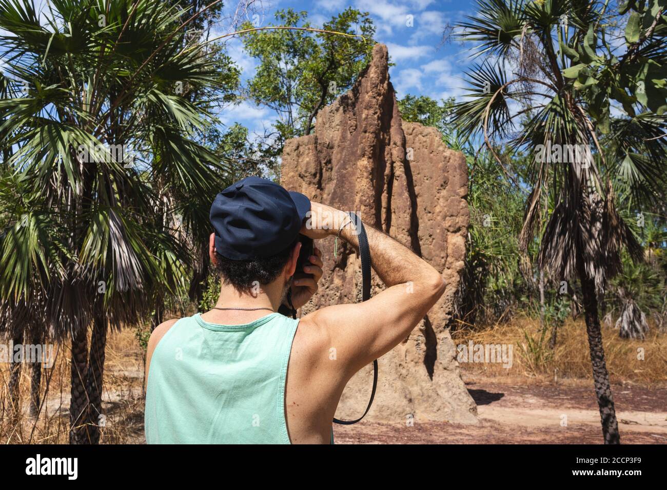 Touriste prenant une photo d'un grand termite magnétique. Convient à un homme tenant un appareil photo, des vêtements décontractés, un bonnet et un t-shirt. Bras forts. Litchfield, Australie Banque D'Images