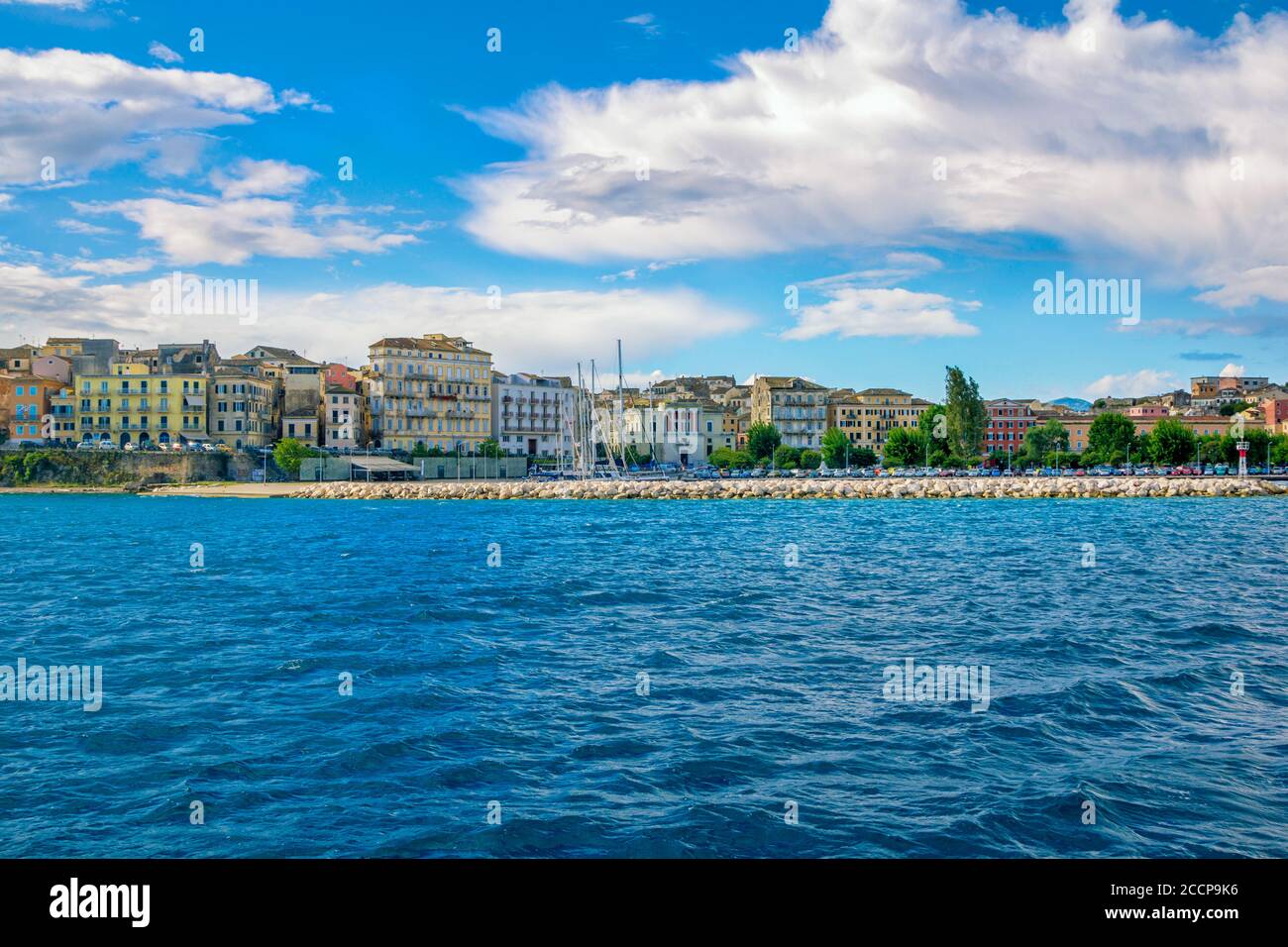 Île de Corfou/Grèce- 7 mai 2019: Kerkyra paysage urbain - baie de mer avec eau turquoise calme, vieilles maisons colorées, ciel bleu avec des nuages blancs et des collines sur Banque D'Images