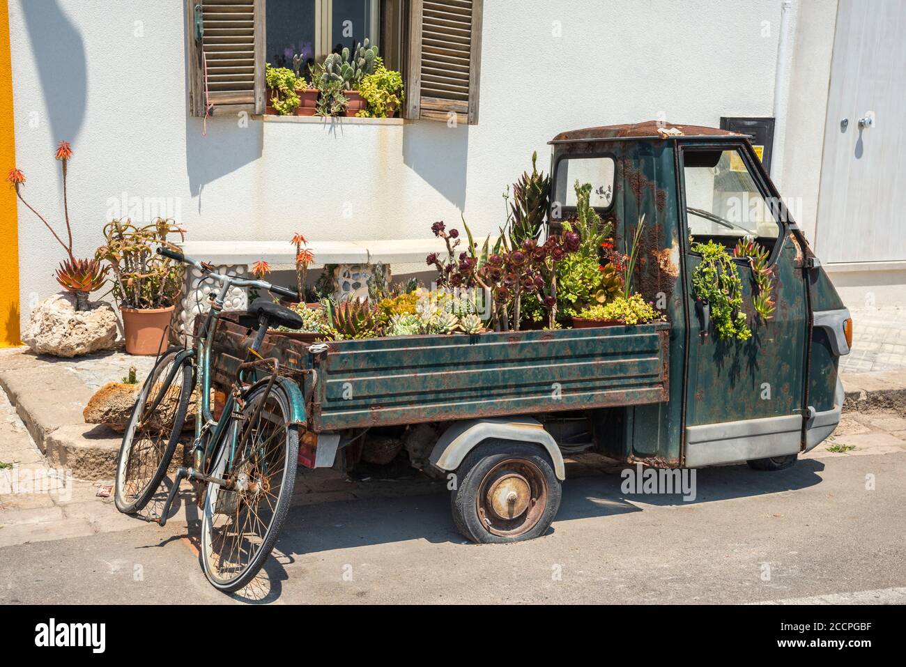 Un vieux piaggio trois roues de ramassage, réutilisé comme conteneur pour les plantes dans la ville de Gallipoli, Puglia du Sud, Italie. Banque D'Images