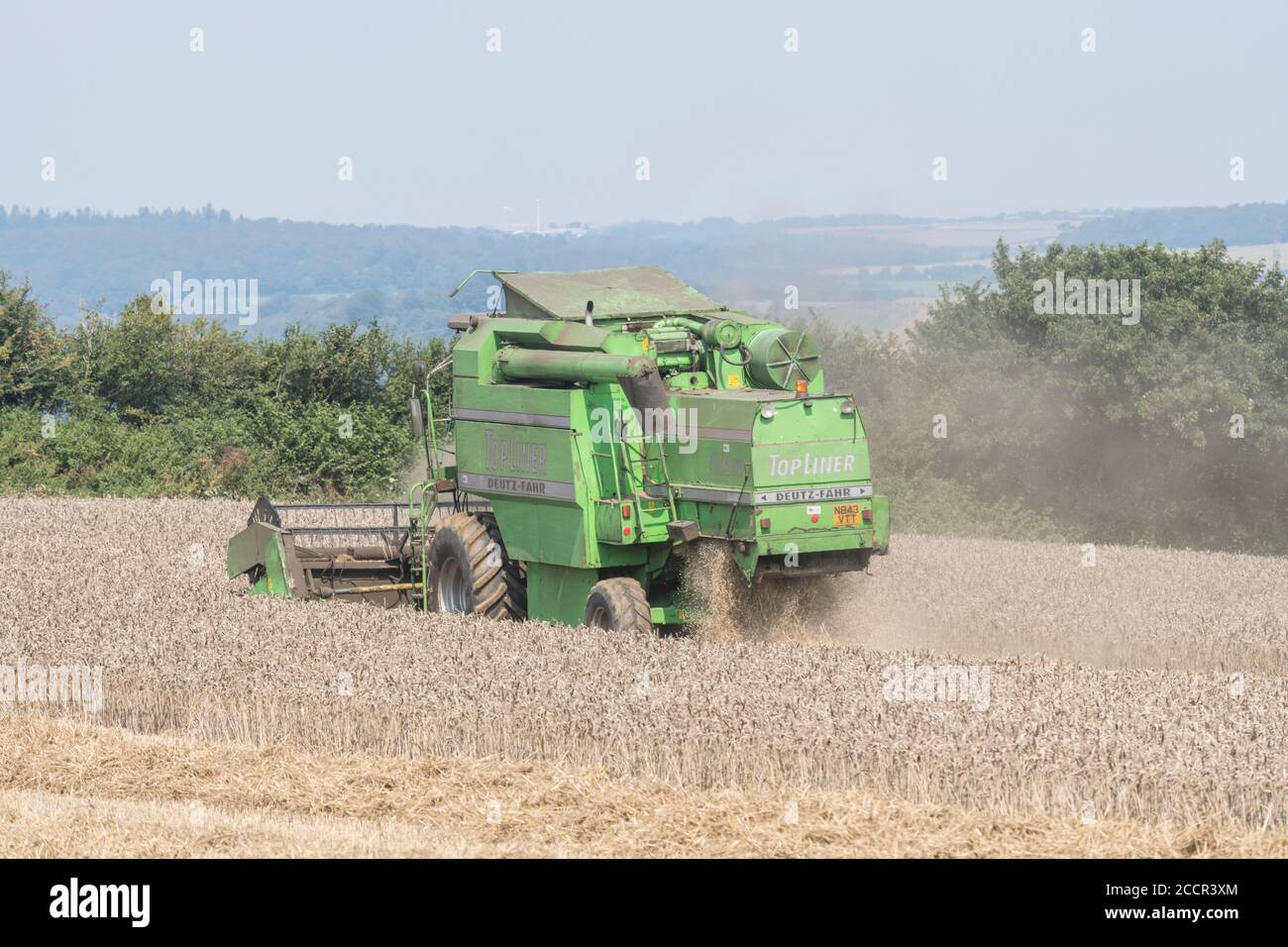 Moissonneuse-batteuse Deutz-Fahr 4065 coupe une récolte de blé 2020 au Royaume-Uni lors d'une journée chaude d'été et remplit d'air de poussière. Rabatteur à dents, tuyau latéral et secoueur visibles. Banque D'Images