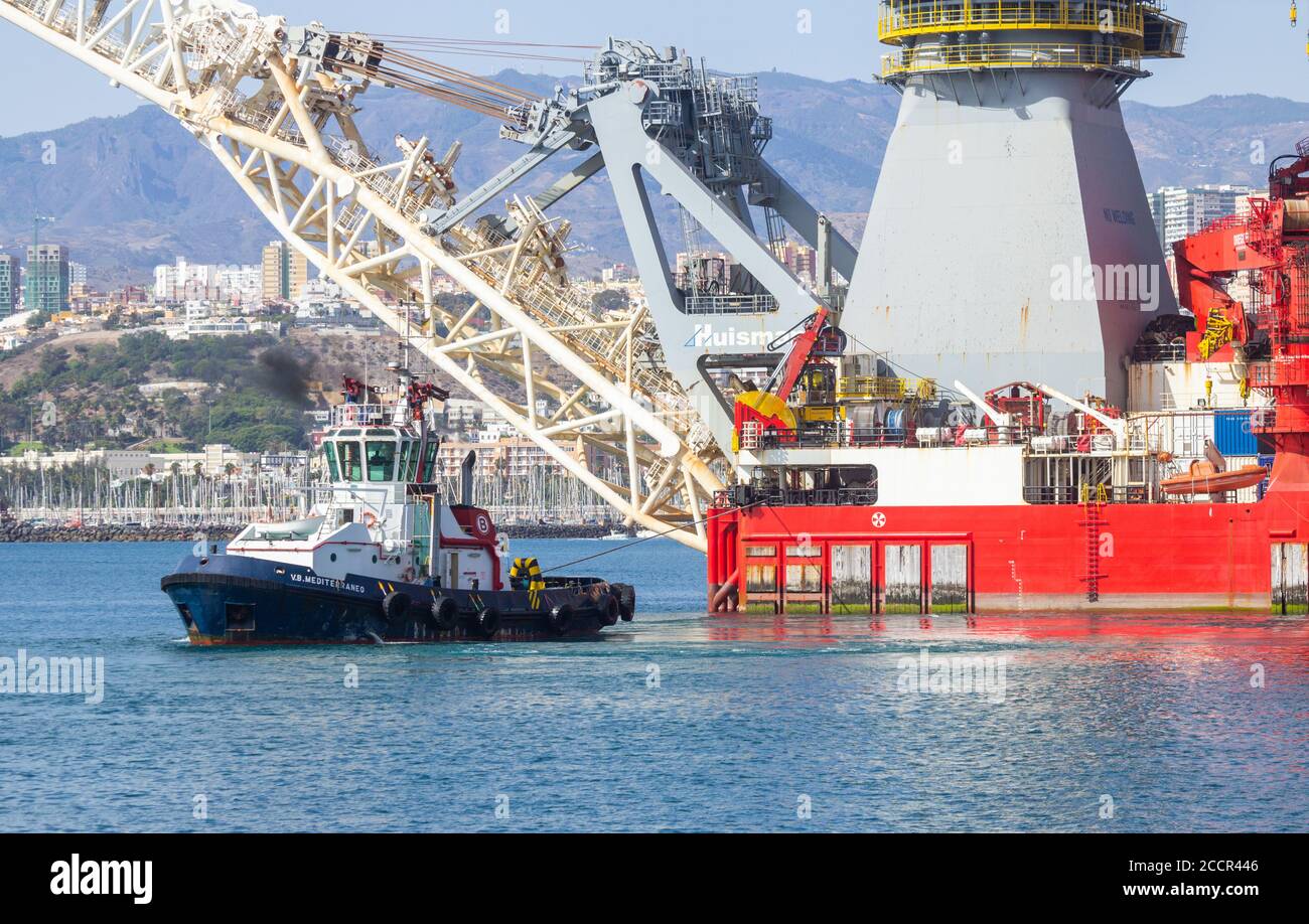 Pipelay de 182 mètres de long et navire de levage lourd, Seven Borialis, étant guidé hors du port de Las Palmas par des remorqueurs. Banque D'Images