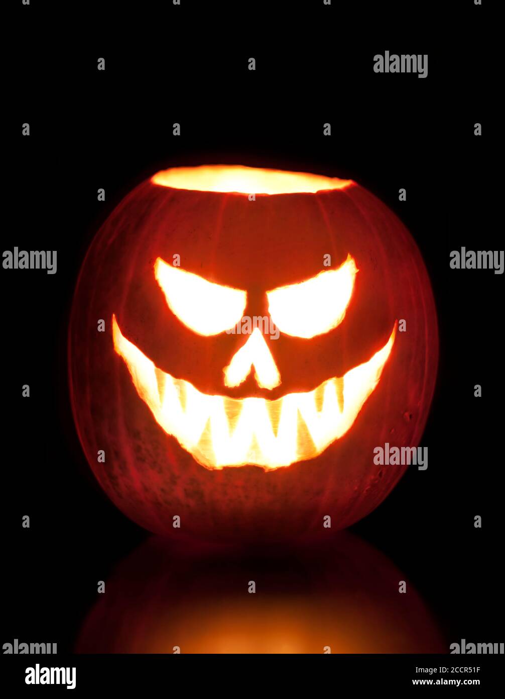Jack O'Lantern illuminé effrayant halloween citrouille sculptée sur fond noir avec espace de copie. Banque D'Images