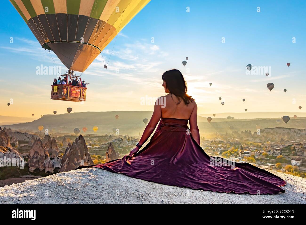 Fille regardant les ballons d'air chaud dans le ciel Banque D'Images