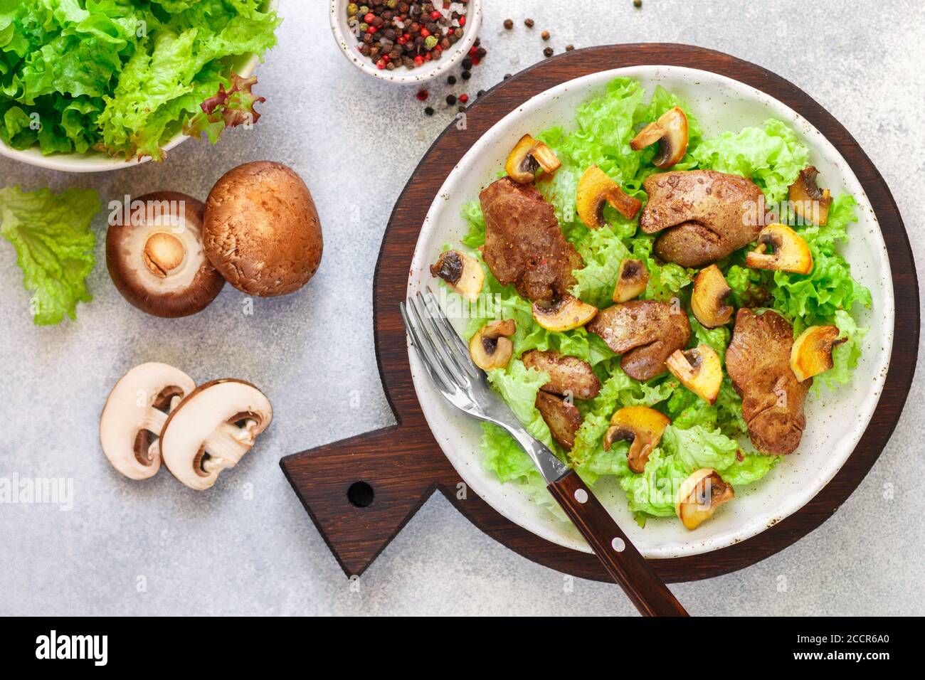 Salade de laitue chaude avec foie de poulet, champignons frits, huile d'olive, assaisonnements et balsamique. Délicieux dîner gastronomique. Mise au point sélective Banque D'Images