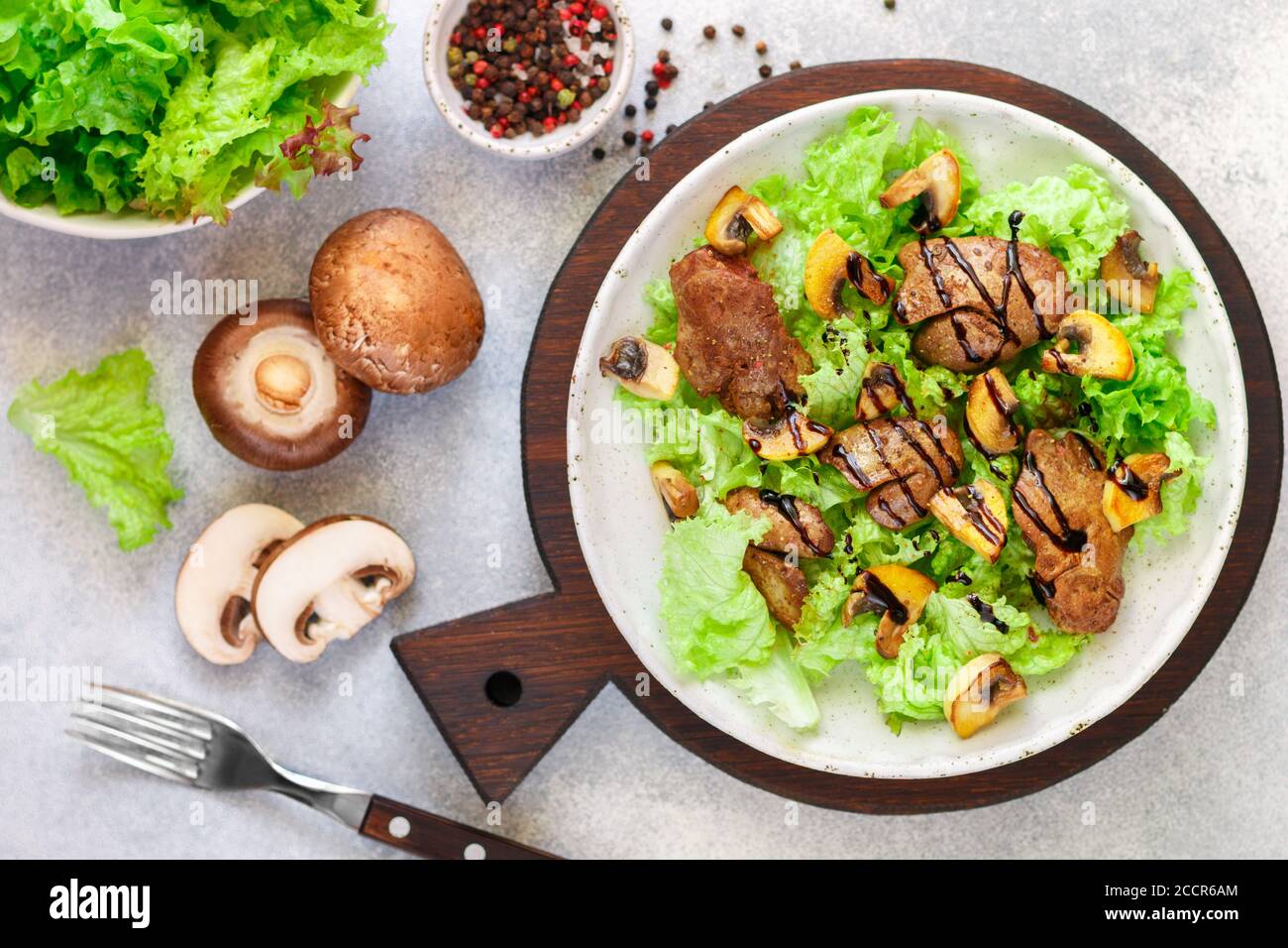 Salade de laitue chaude avec foie de poulet, champignons frits, huile d'olive, assaisonnements et balsamique. Délicieux dîner gastronomique. Mise au point sélective Banque D'Images