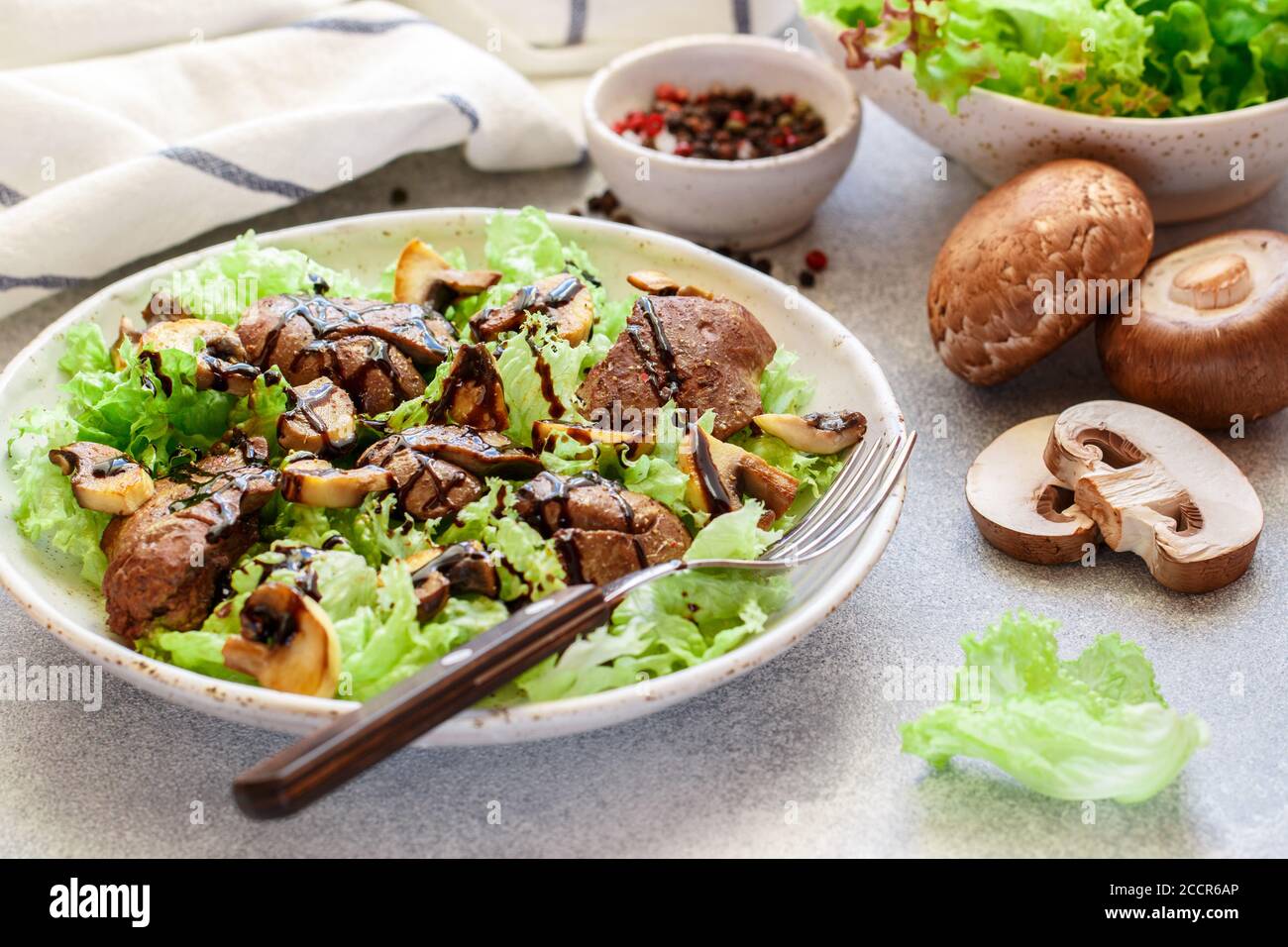 Salade de laitue chaude avec foie de poulet, champignons frits, huile d'olive, assaisonnements et balsamique. Délicieux dîner gastronomique. Mise au point sélective Banque D'Images
