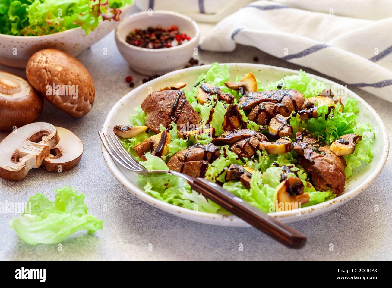 Salade de laitue chaude avec foie de poulet, champignons frits, huile d'olive, assaisonnements et balsamique. Délicieux dîner gastronomique. Mise au point sélective Banque D'Images