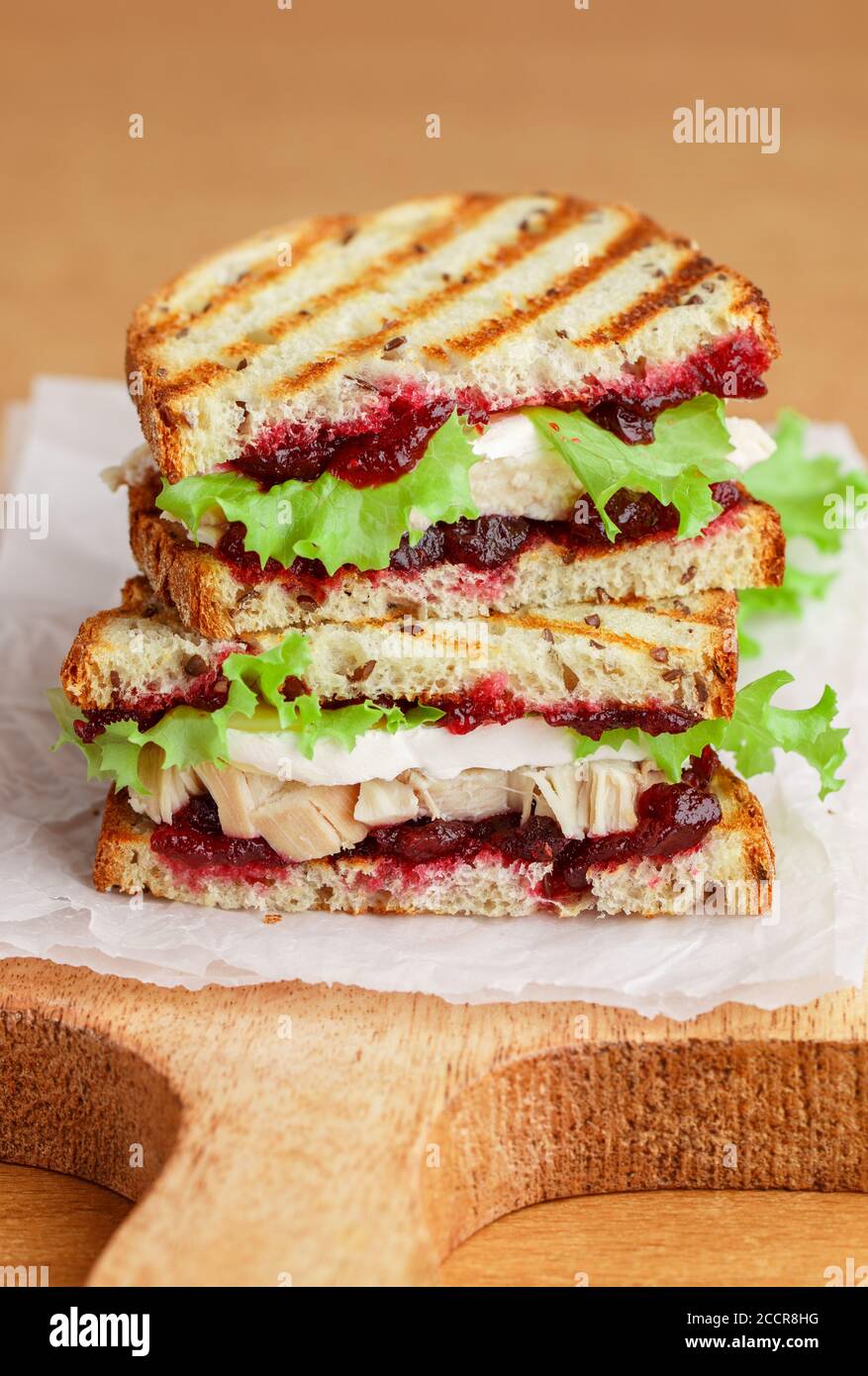 Délicieux sandwich à la dinde ou au poulet avec du fromage brie ou Camembert, de la laitue et du chutney aux canneberges (lingonberry, cowberry) sur du pain aux céréales avec du lin See Banque D'Images