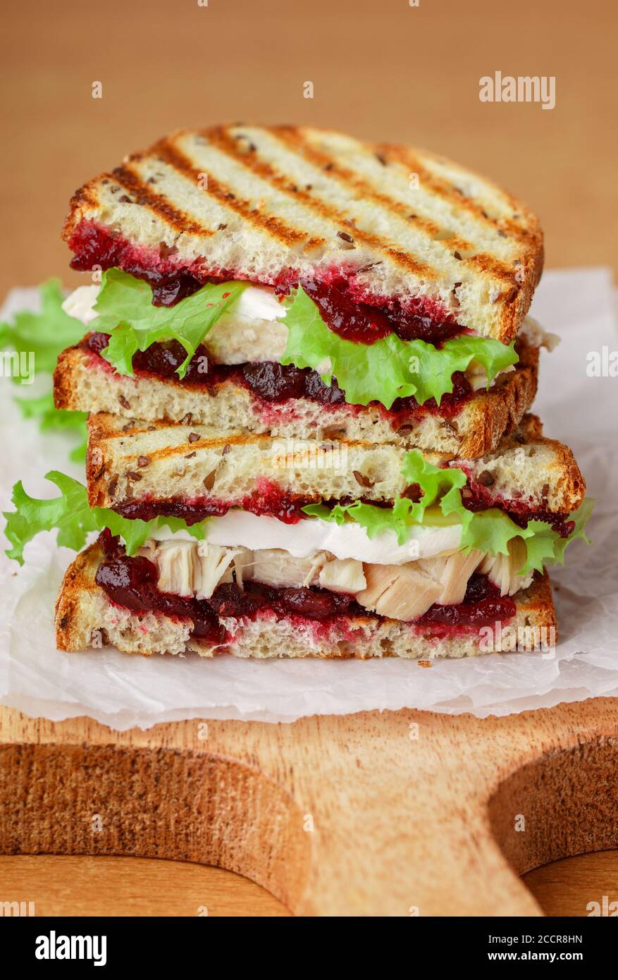 Délicieux sandwich à la dinde ou au poulet avec du fromage brie ou Camembert, de la laitue et du chutney aux canneberges (lingonberry, cowberry) sur du pain aux céréales avec du lin See Banque D'Images