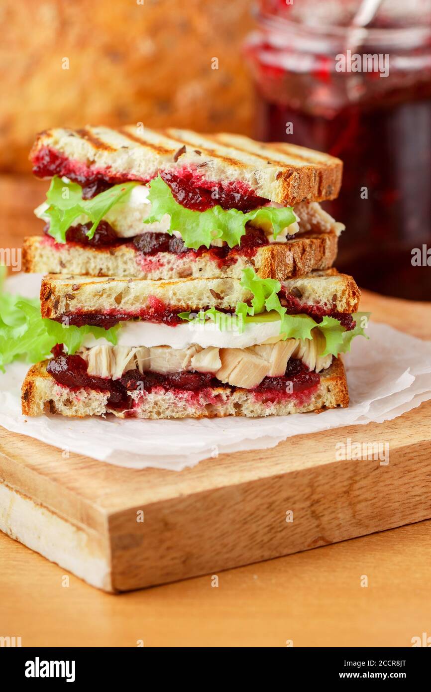 Délicieux sandwich à la dinde ou au poulet avec du fromage brie ou Camembert, de la laitue et du chutney aux canneberges (lingonberry, cowberry) sur du pain aux céréales avec du lin See Banque D'Images