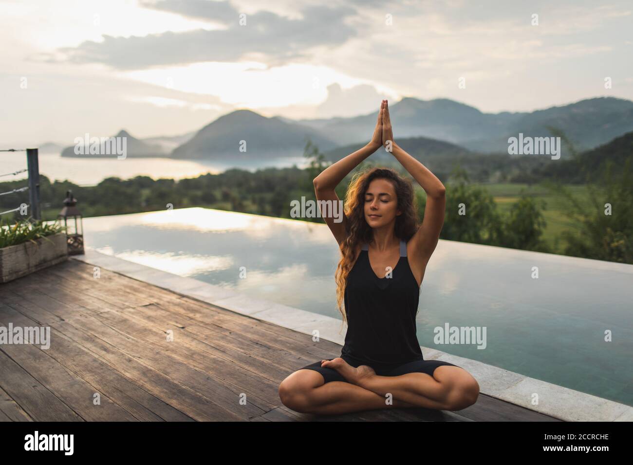 Femme méditant seule sur la piscine à débordement avec belle vue sur l'océan et la montagne le matin. Mode de vie sain, concept spirituel et émotionnel. Éveil, harmonie avec la nature. Banque D'Images
