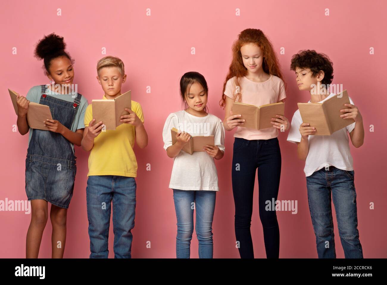 Divers élèves industriels lisant des livres, se préparer à l'école sur fond rose Banque D'Images