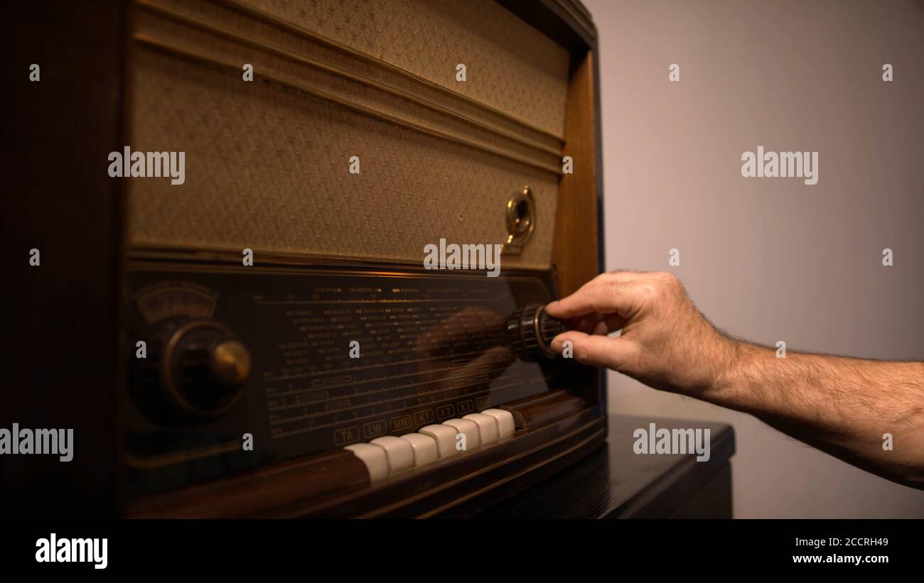 Homme à la recherche de la station de radio sur la radio d'époque. Photo de  haute qualité Photo Stock - Alamy