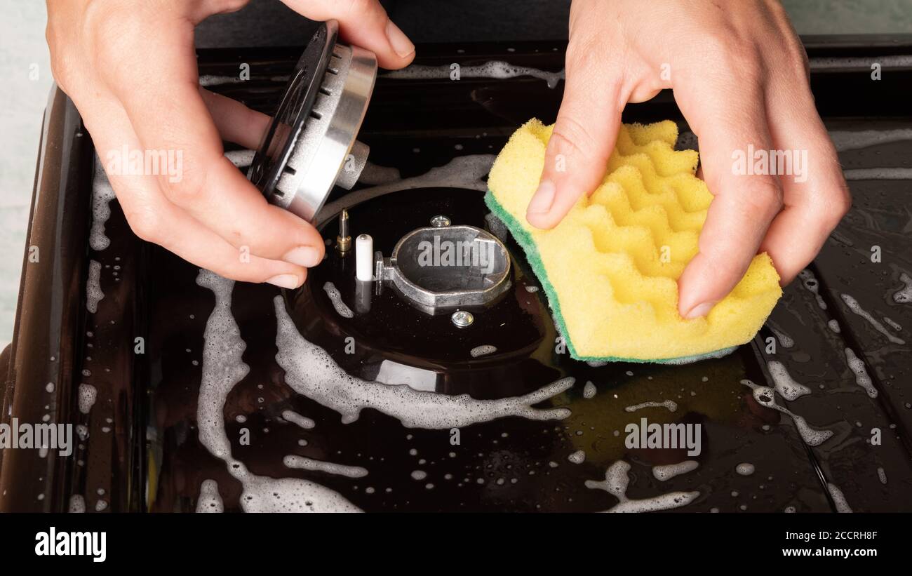 nettoyage de la cuisine, appareils, nettoyage de la surface de la cuisinière à gaz, brûleur nettoyage linge de toilette jaune gros plan. Banque D'Images