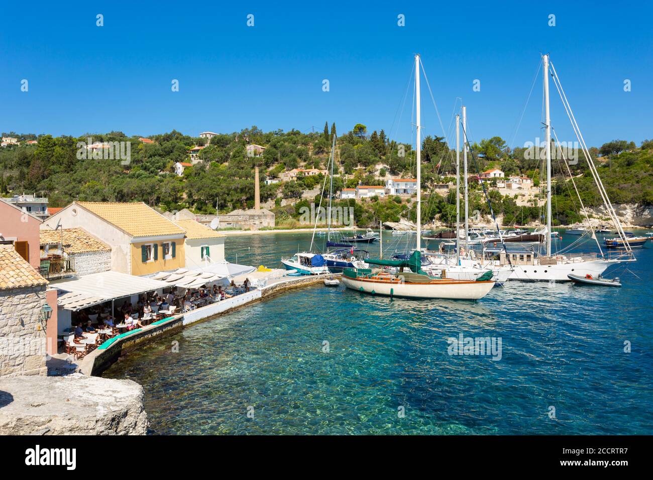 Taverne en bord de mer et bateaux au port de Longos, Paxos, Iles Ioniennes, Grèce Banque D'Images