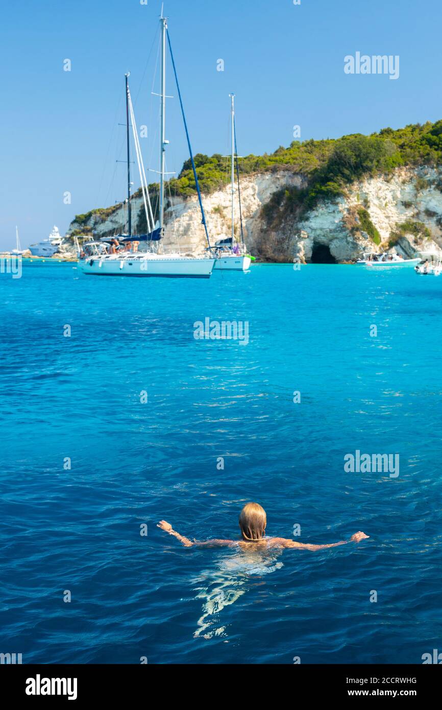 Une fille blonde nageant dans l'eau claire au large de la côte d'Antipaxos, Iles Ioniennes, Grèce Banque D'Images