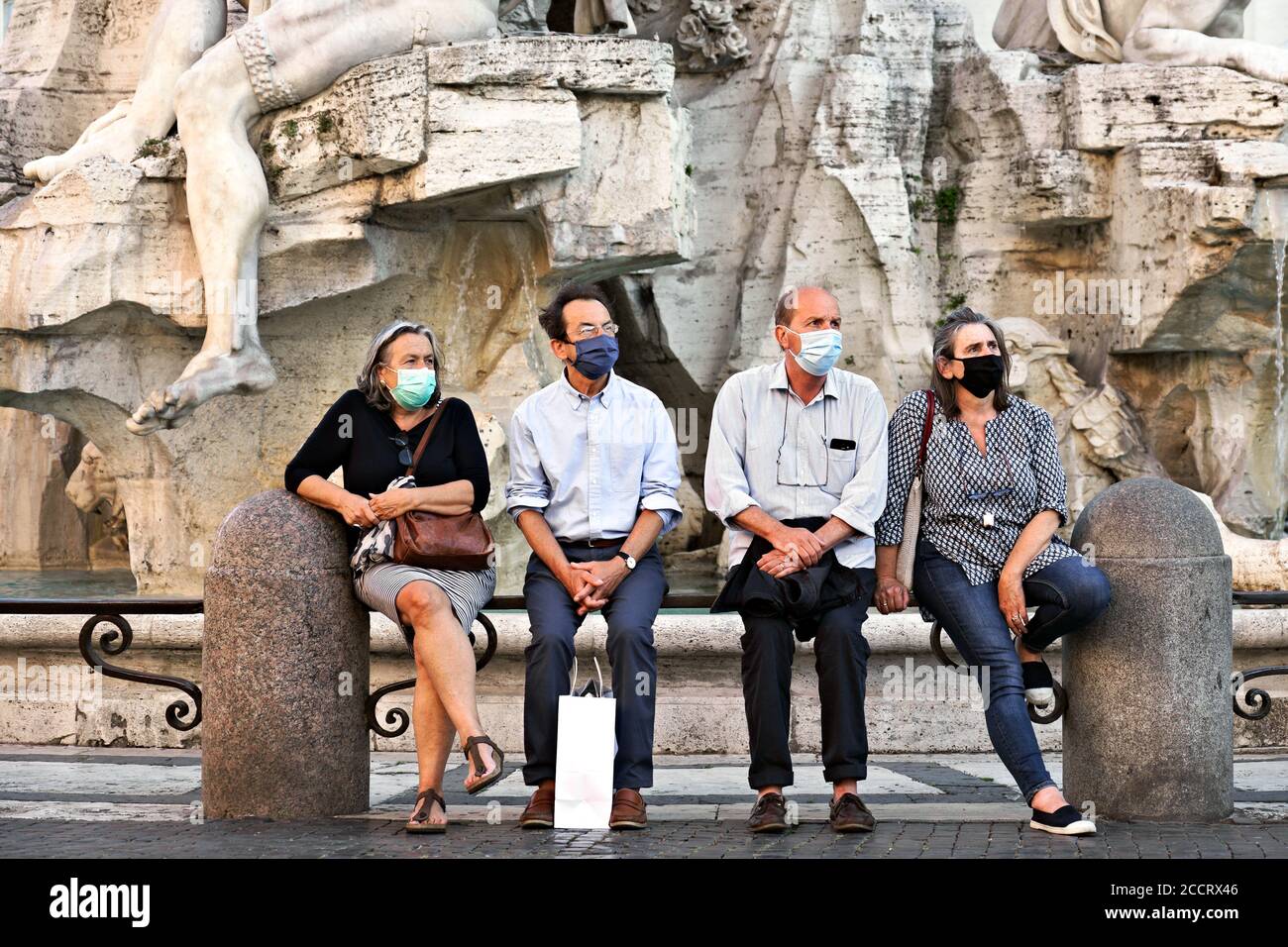 Les touristes portant des masques Covid 19, assis à la fontaine des quatre fleuves de la place Navona, admirent la beauté des arts environnants Rome, Italie, Europe Banque D'Images