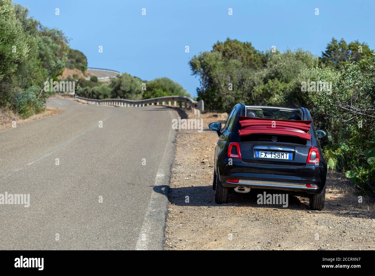 Sant'Antioco, Italie - 07 18 2020: Route côtière dans le sud de la Sardaigne en été avec une Fiat 500 cabriolet en premier plan. Banque D'Images