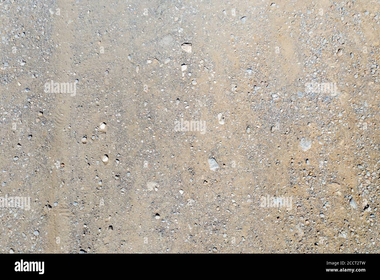 Au-dessus de la vue du sol, sol brun, terre aride sablonneuse avec de minuscules pierres comme fond, texture, matériau. Vider la route rurale sèche avec le tracé de roue. Banque D'Images