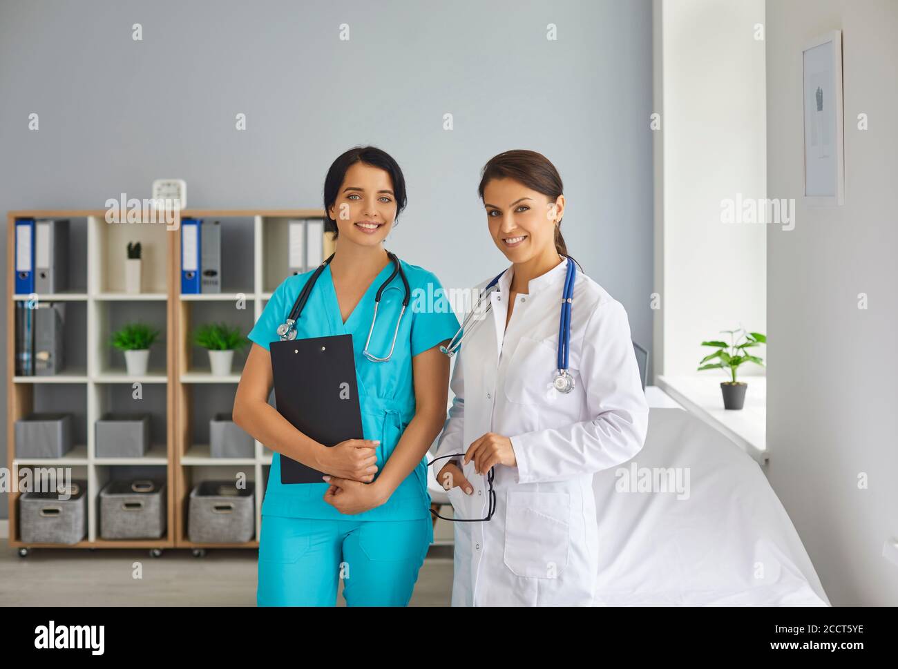 Jeune médecin souriant et infirmière regardant la caméra en médecine clinique Banque D'Images