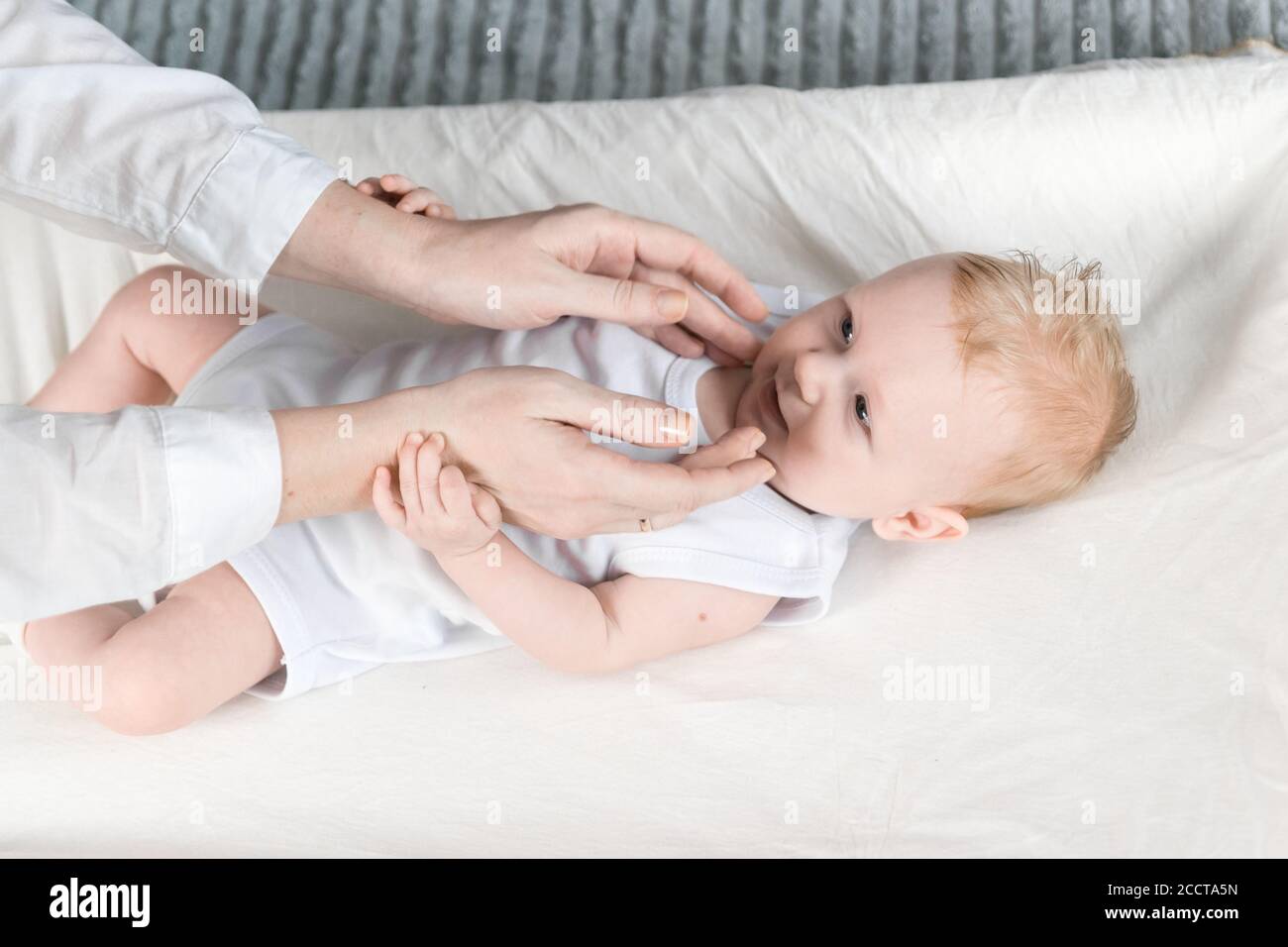 Les Femmes Massent Les Mains D Un Bebe Magnifique Dans Un Body Blanc Le Bebe Est Allonge Sur La Table A Langer Et Regarde Sa Mere Photo Stock Alamy