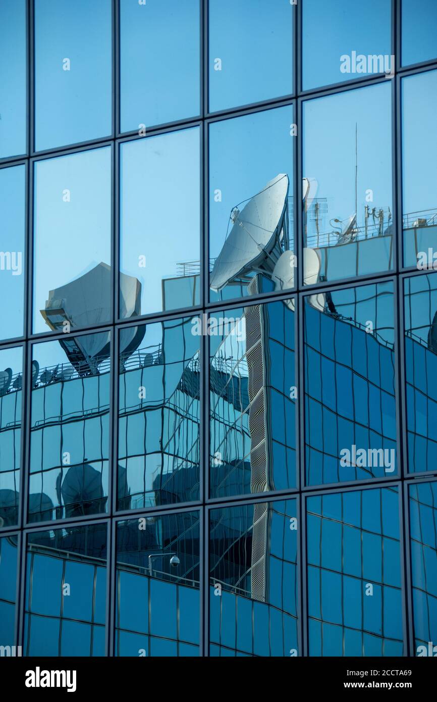 Des plats satellites se reflètent dans les fenêtres d'un bureau moderne bâtiment Banque D'Images