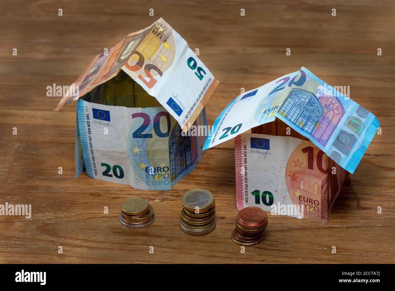 Deux maisons en billets de banque de 50, 20 et 10 euros avec des piles de pièces en euros Banque D'Images