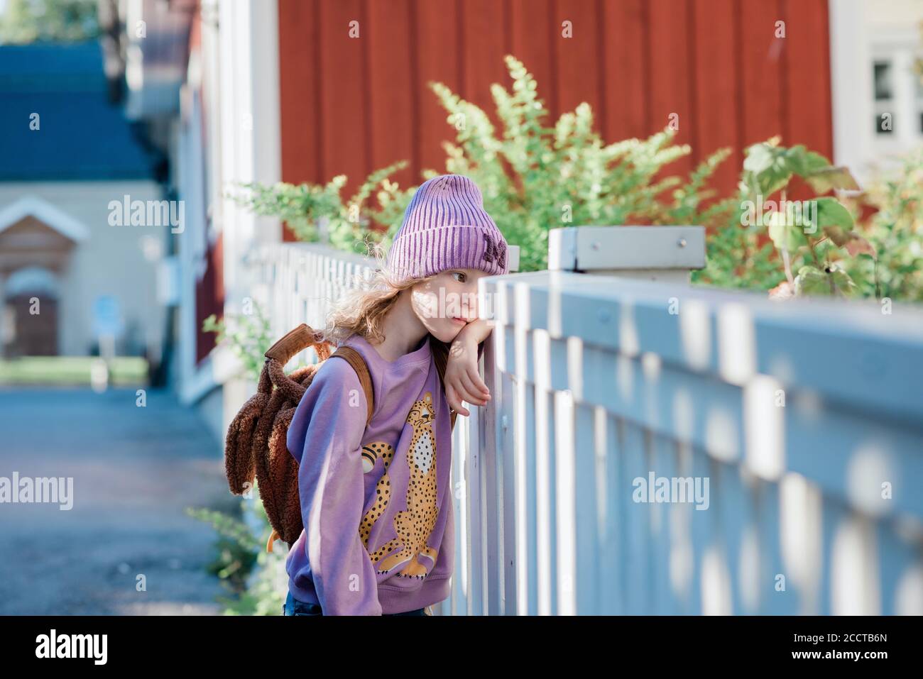 portrait d'une jeune fille penchée sur une clôture en attente pour l'école Banque D'Images