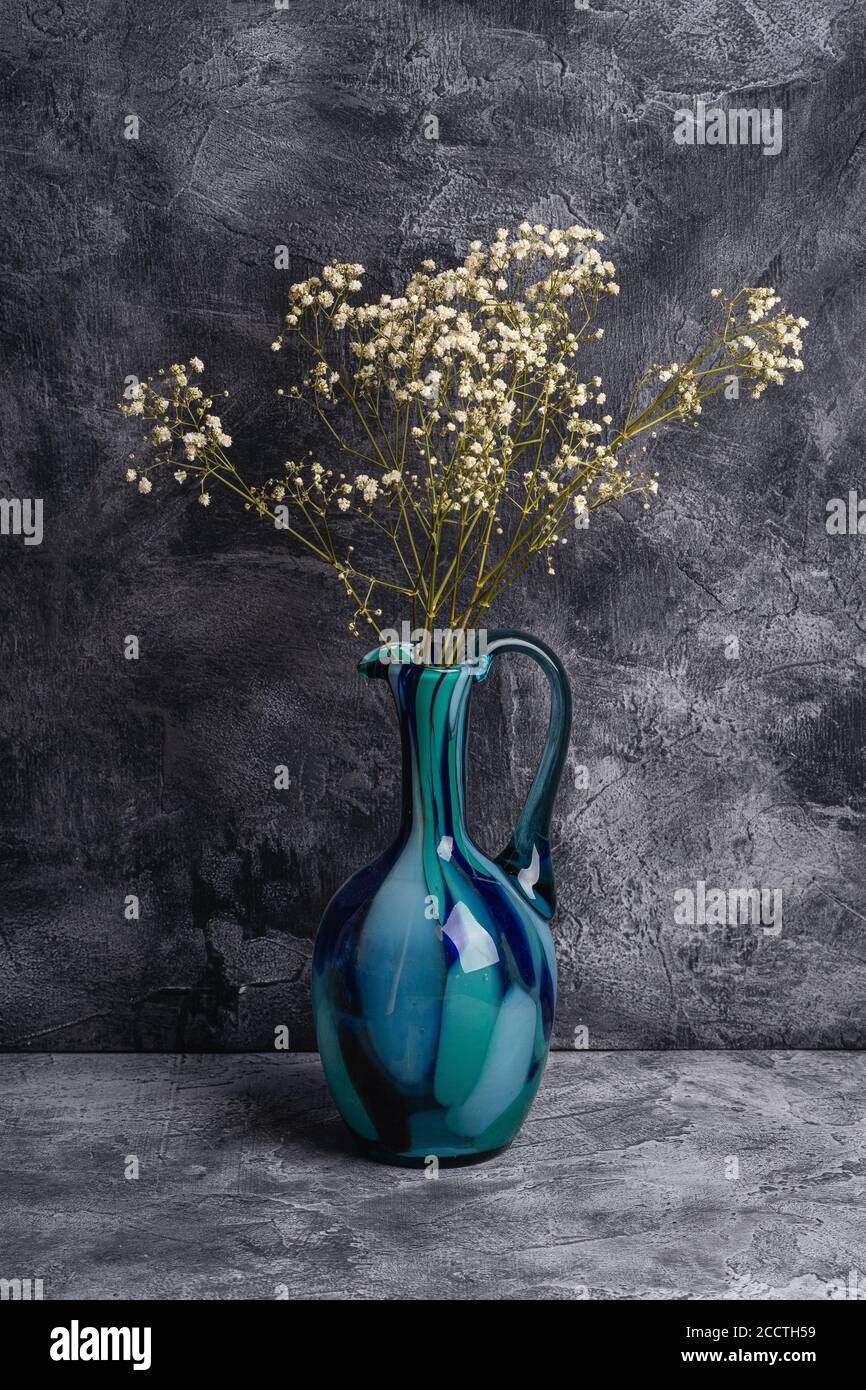 Vase en pot bleu avec fleurs blanches séchées en vrac de gitsophila sur fond de pierre texturé foncé, vue en angle Banque D'Images