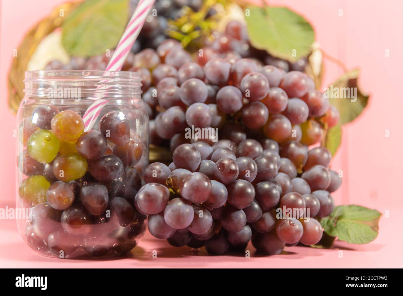 Pot avec grains et grappes de raisin. Jus de raisin. Boisson rafraîchissante. Boisson aux fruits. Ingrédients pour vins et jus. Fruits frais. Raisin rose. Banque D'Images
