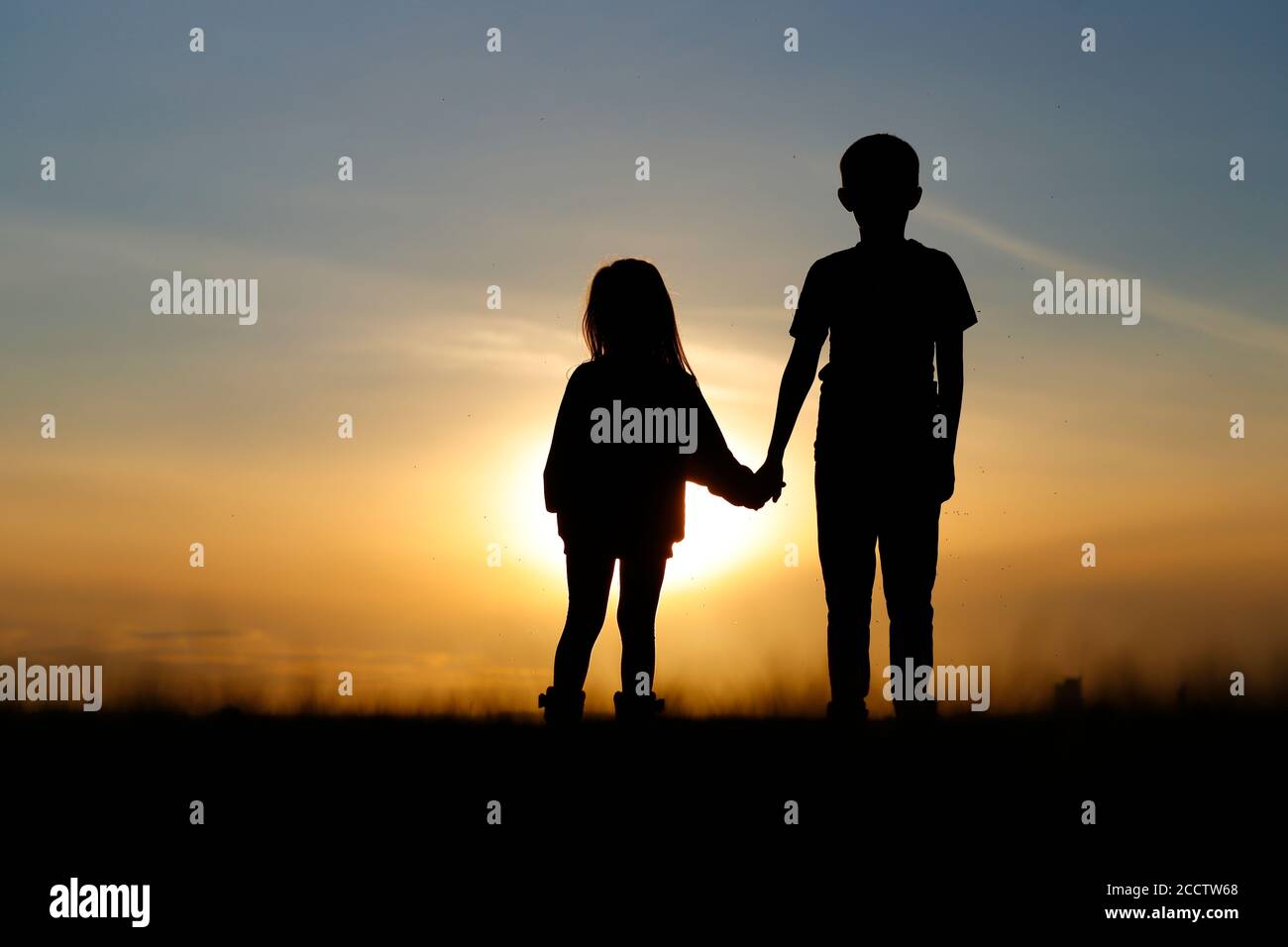 Silhouette de 2 jeunes frères et sœurs regardant le coucher du soleil Leeds Banque D'Images